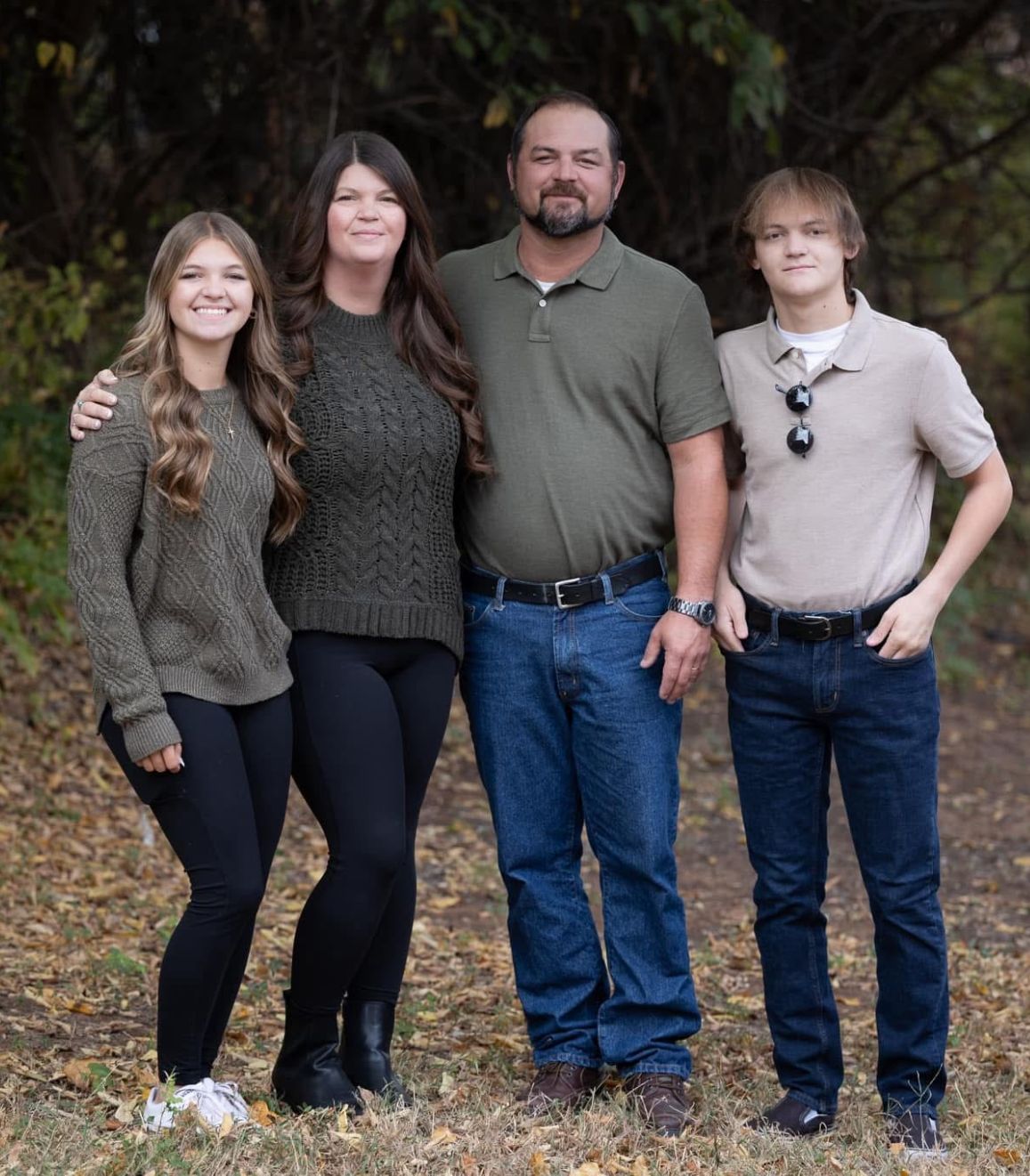 A family posing for a picture together in the woods