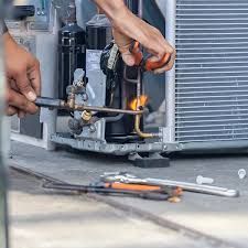 A man is working on an air conditioner with a torch.