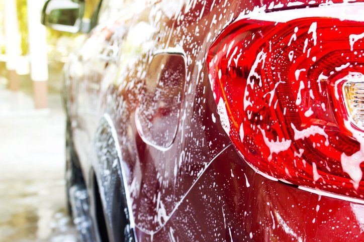 Foam of car wash on red car.