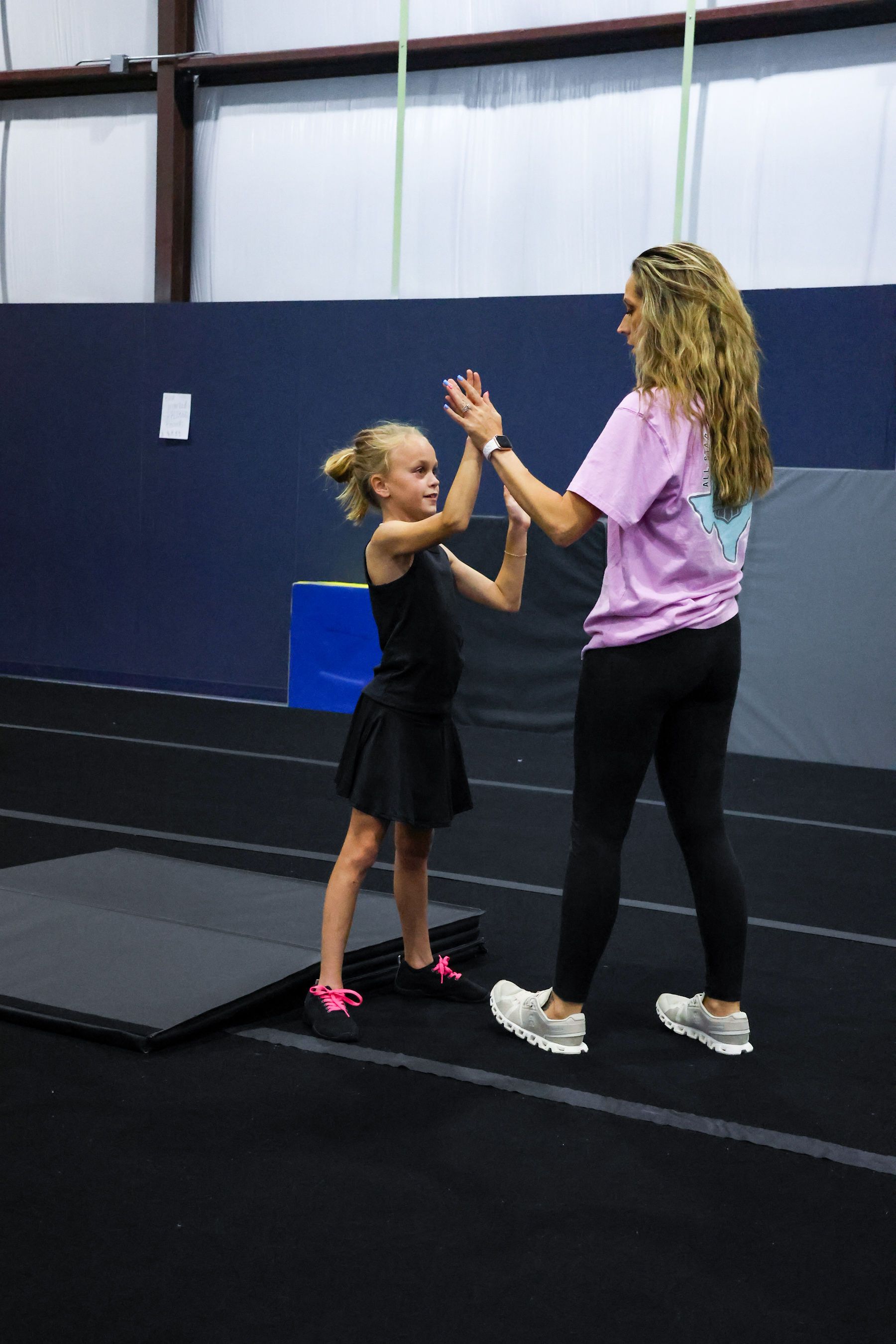 A group of cheerleaders are doing a pyramid on a blue mat
