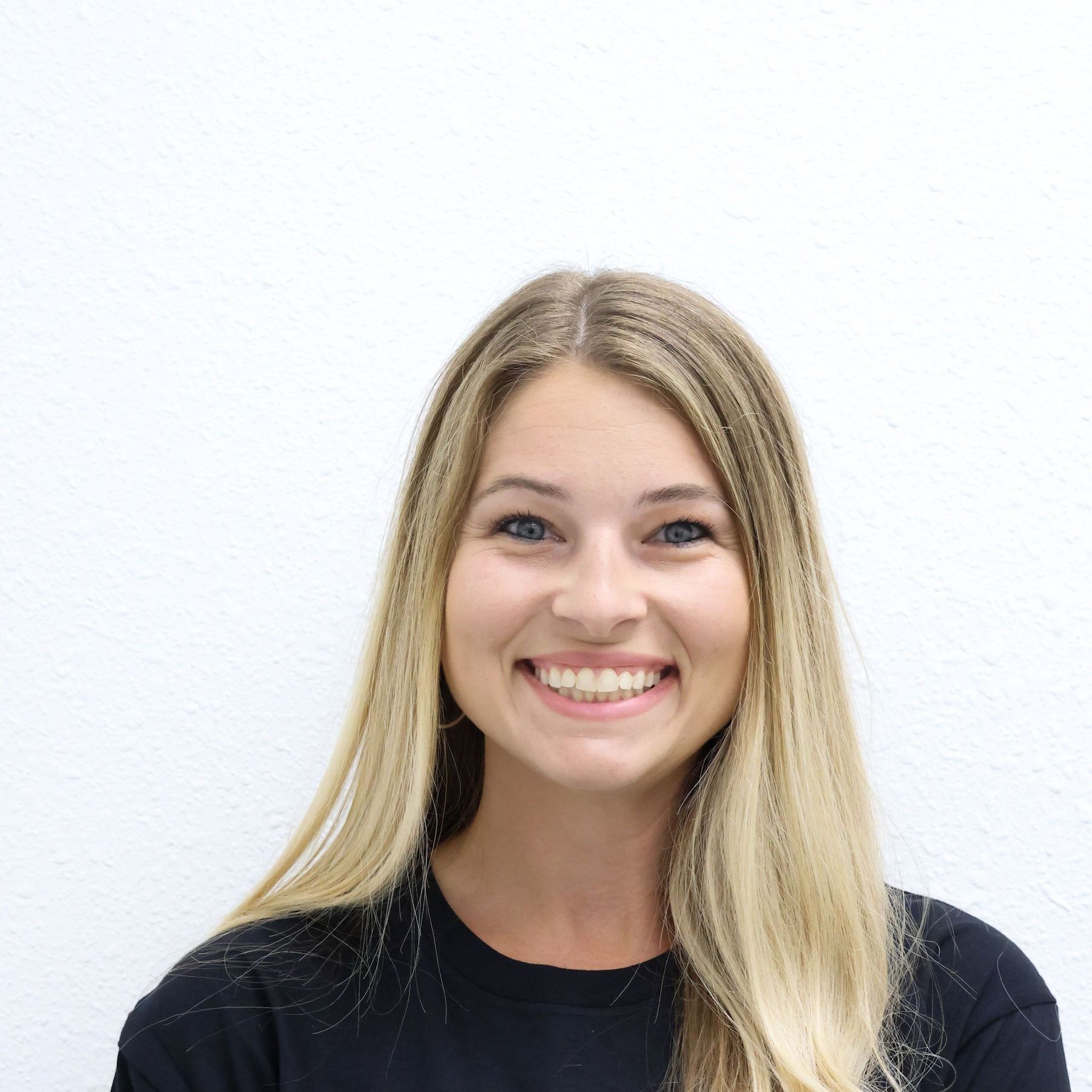 A man with a beard is standing with his arms crossed in a gym.