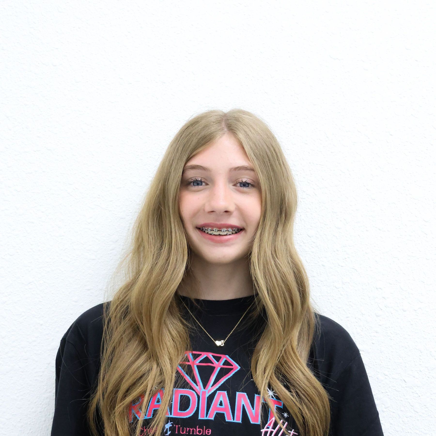 A woman is holding a clipboard and smiling in a gym.