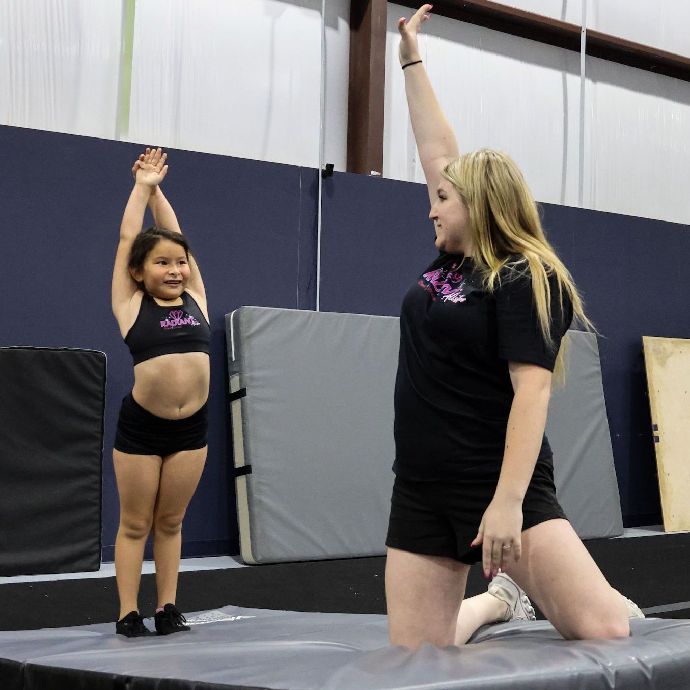 A group of young girls in blue and white uniforms are holding pom poms in their hands.