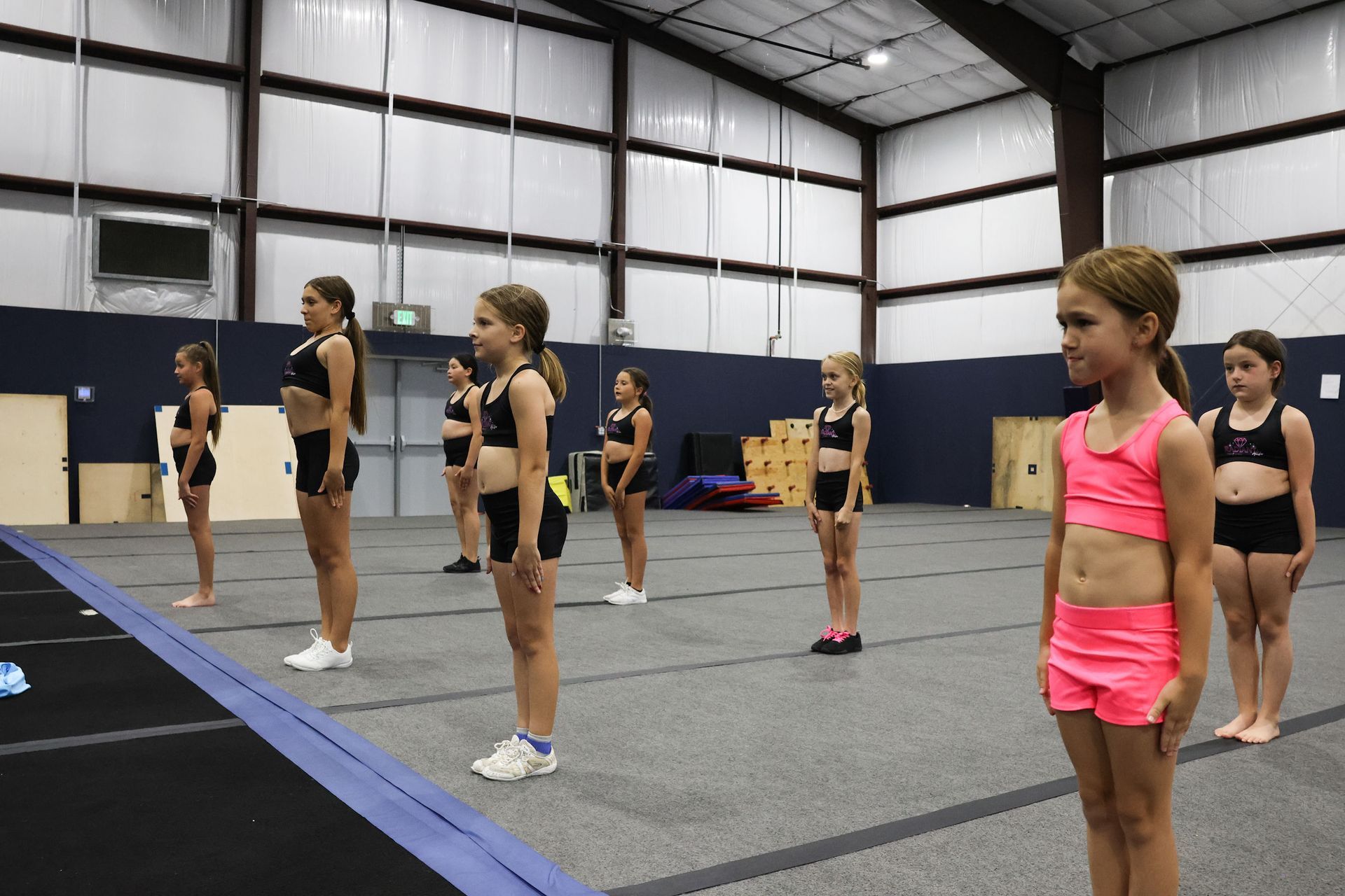 A group of young girls are doing splits on the floor in a dance studio.
