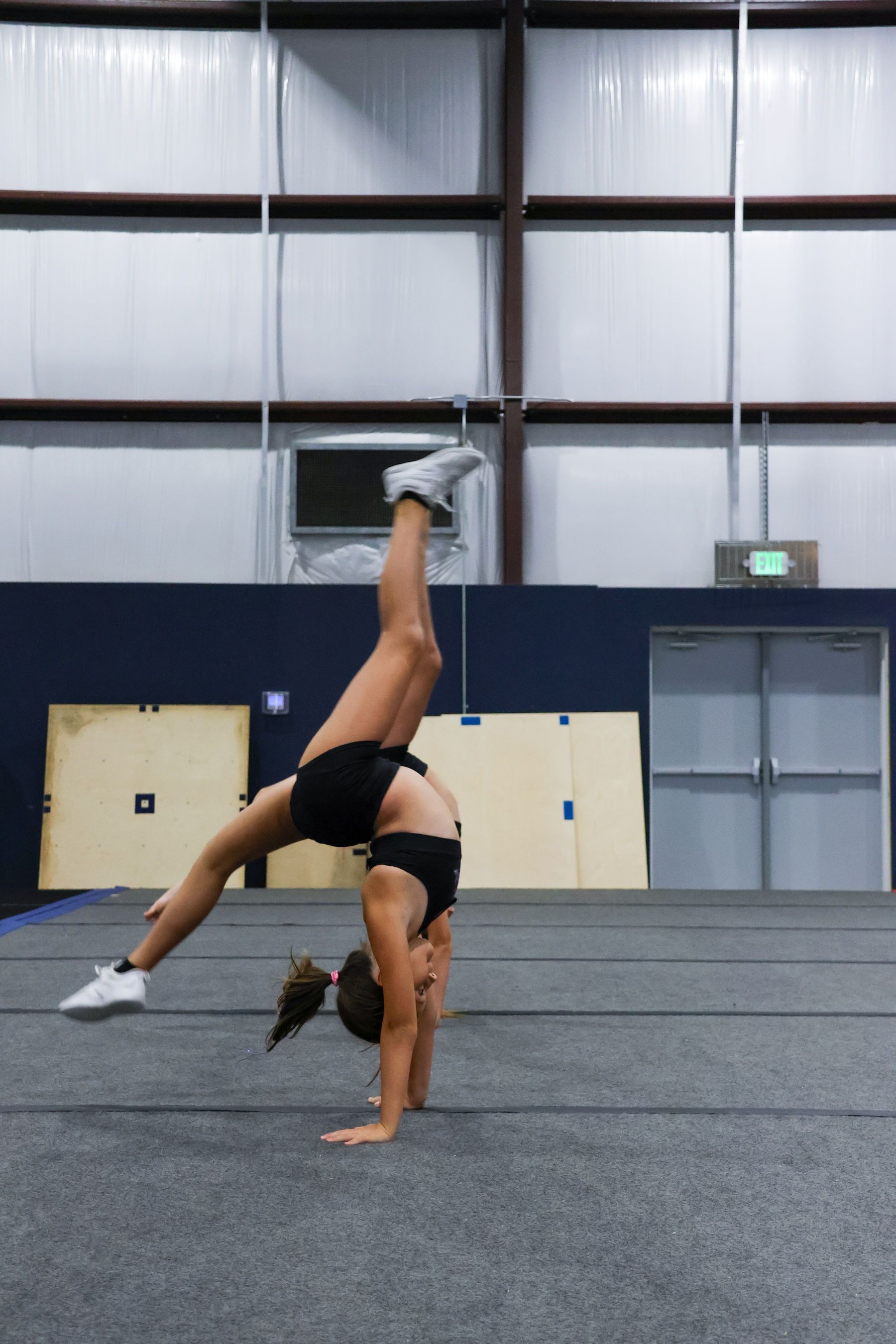 A young girl in a cheerleading uniform is holding pom poms in the air.