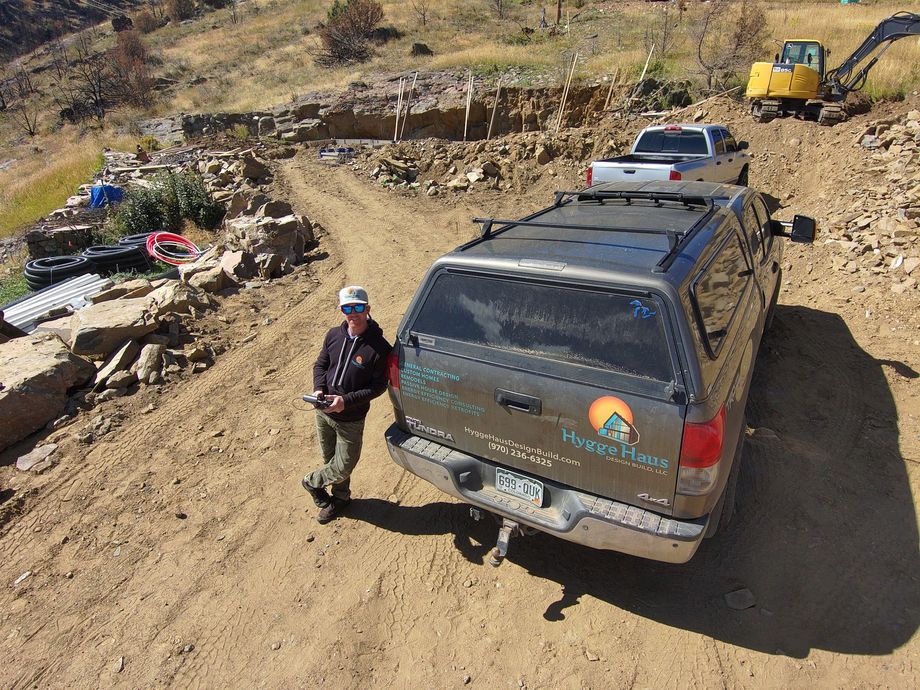 A man is standing next to a ford expedition on a dirt road.
