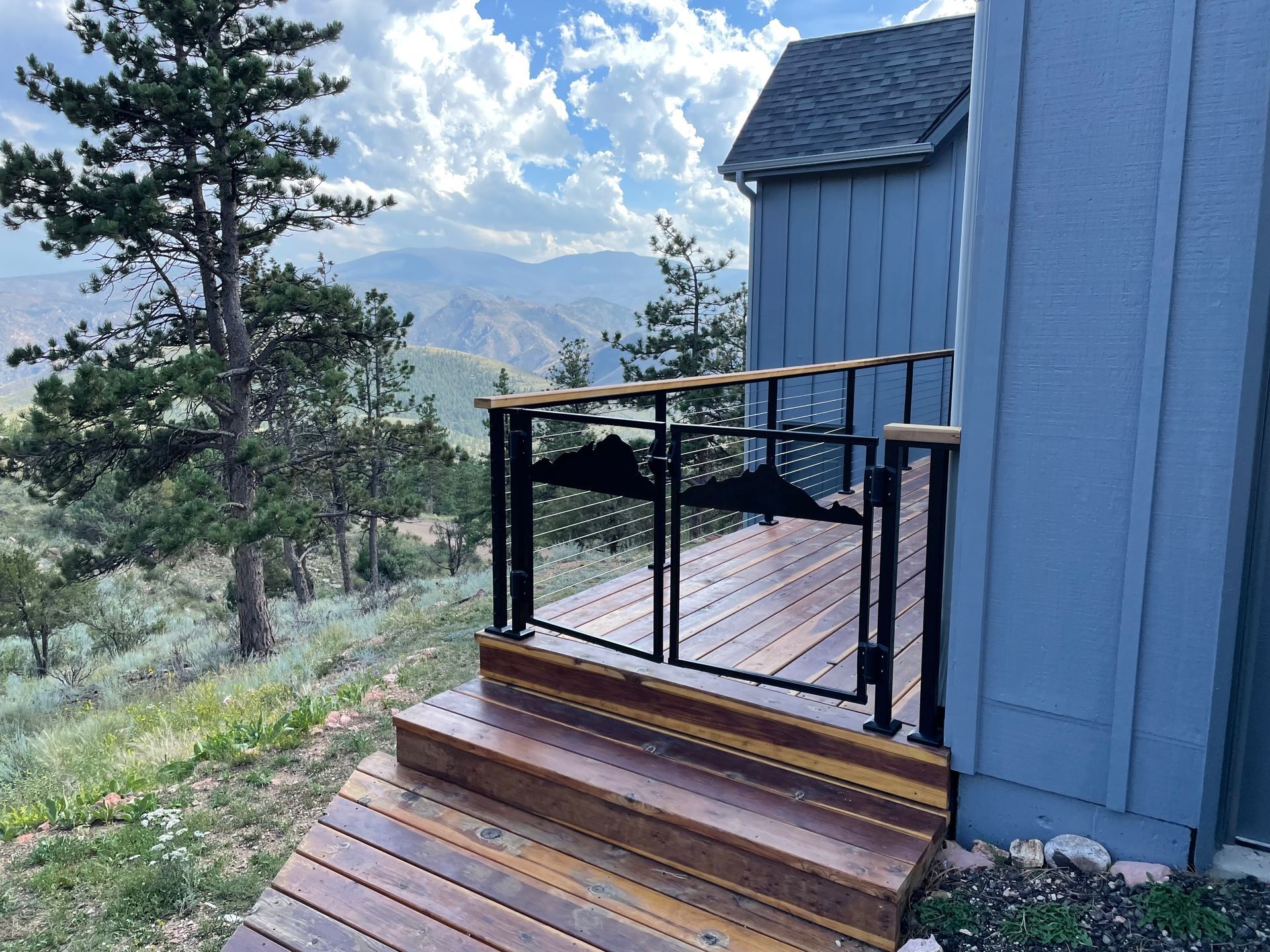 A wooden deck with stairs leading up to a house with a view of the mountains.