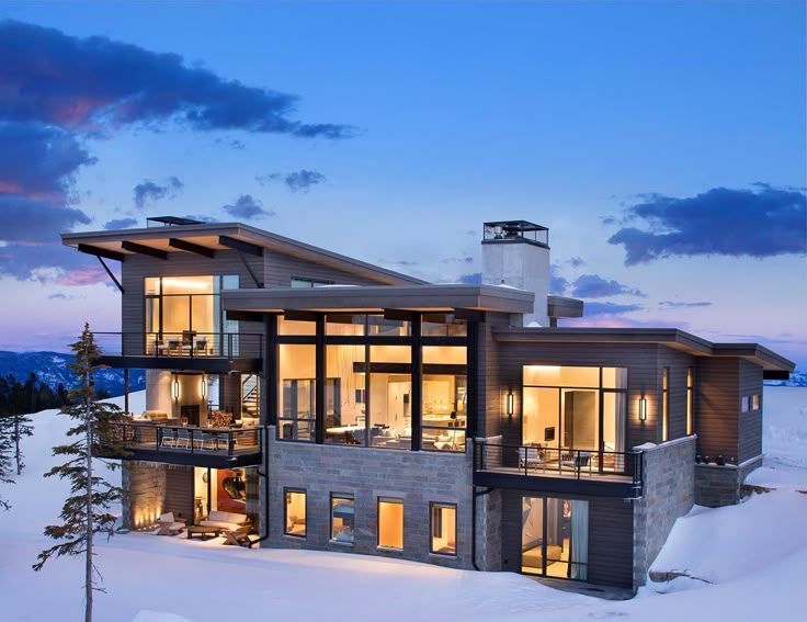 A large house is sitting on top of a snow covered hill.
