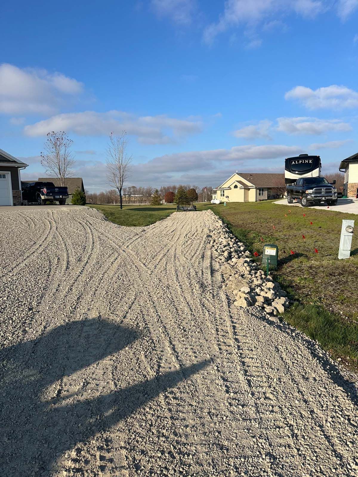 A gravel driveway leading to a house in a residential area.