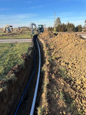 A pipe is being installed in a trench in a field.