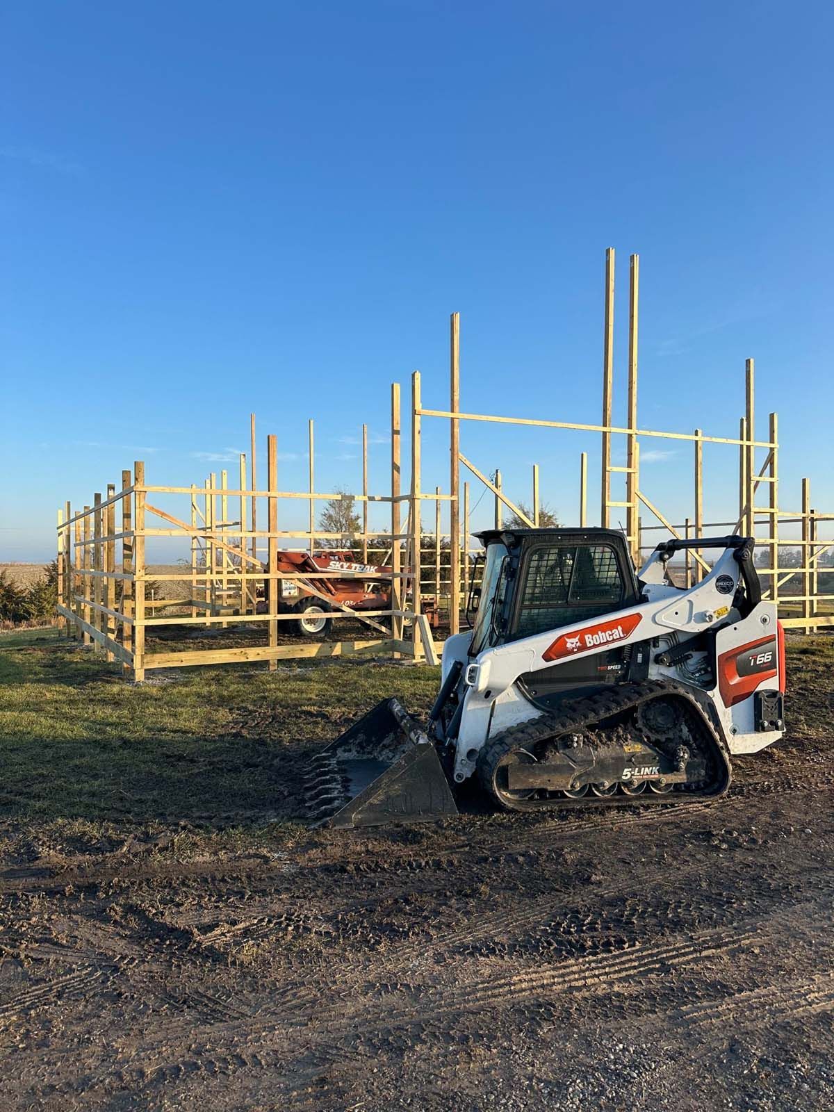 A bobcat is parked in front of a building under construction.