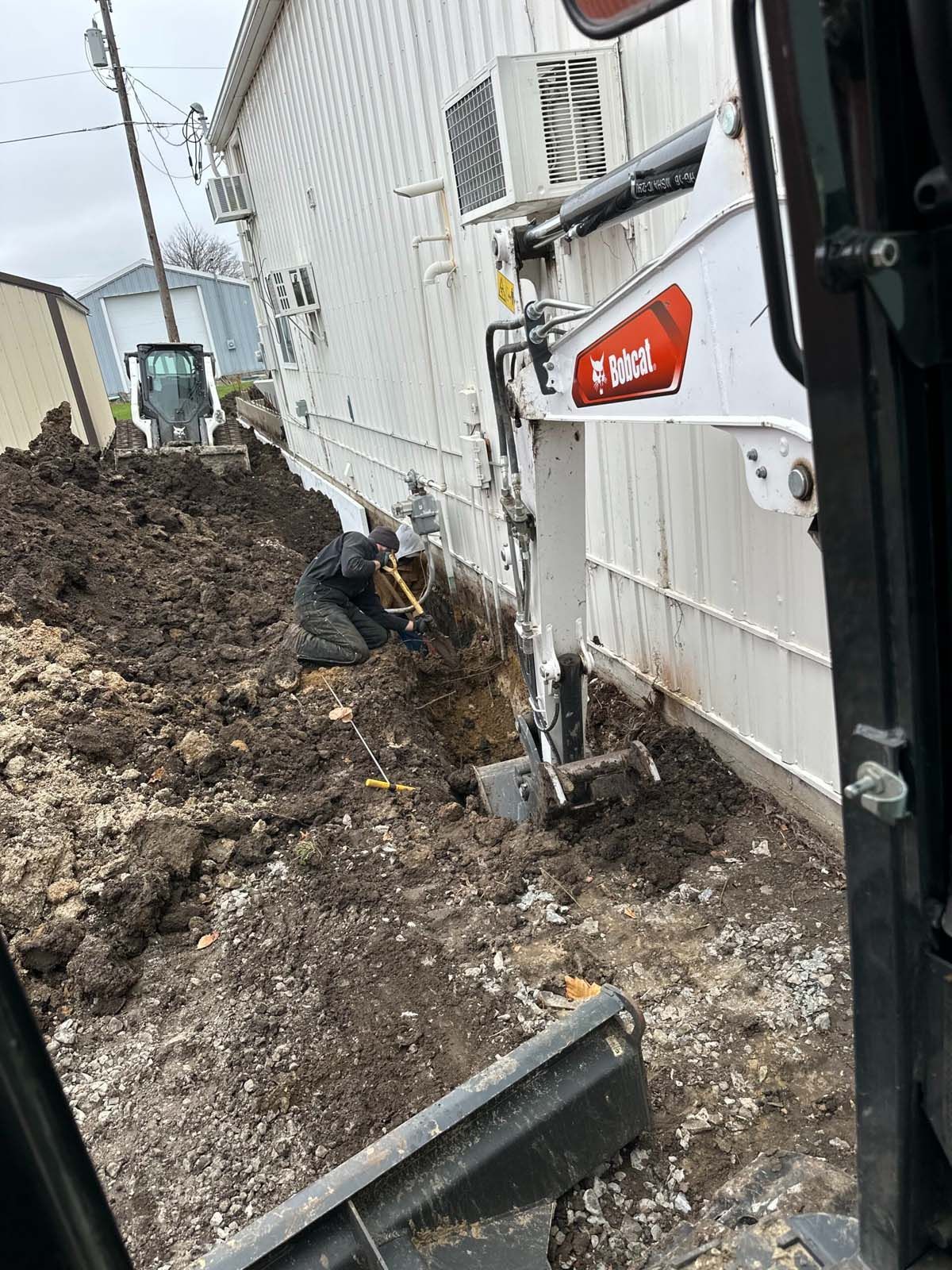 A man is digging a hole in the ground next to a building.