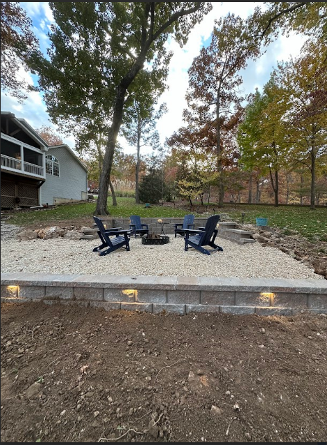 A brick wall is being built in a dirt field next to a tree.