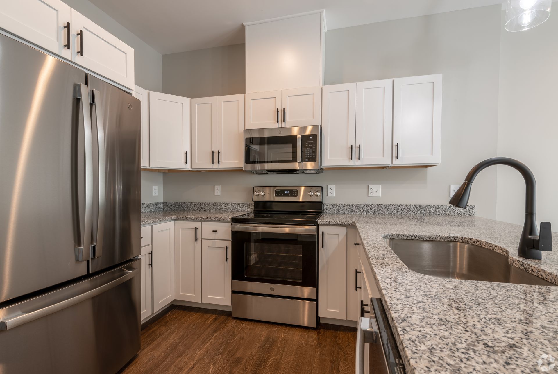 a kitchen with white cabinets , stainless steel appliances , granite counter tops and a sink .