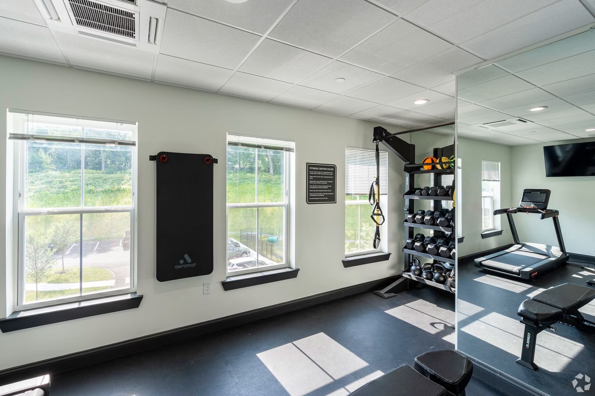 a gym with a treadmill , dumbbells , and a mirror .
