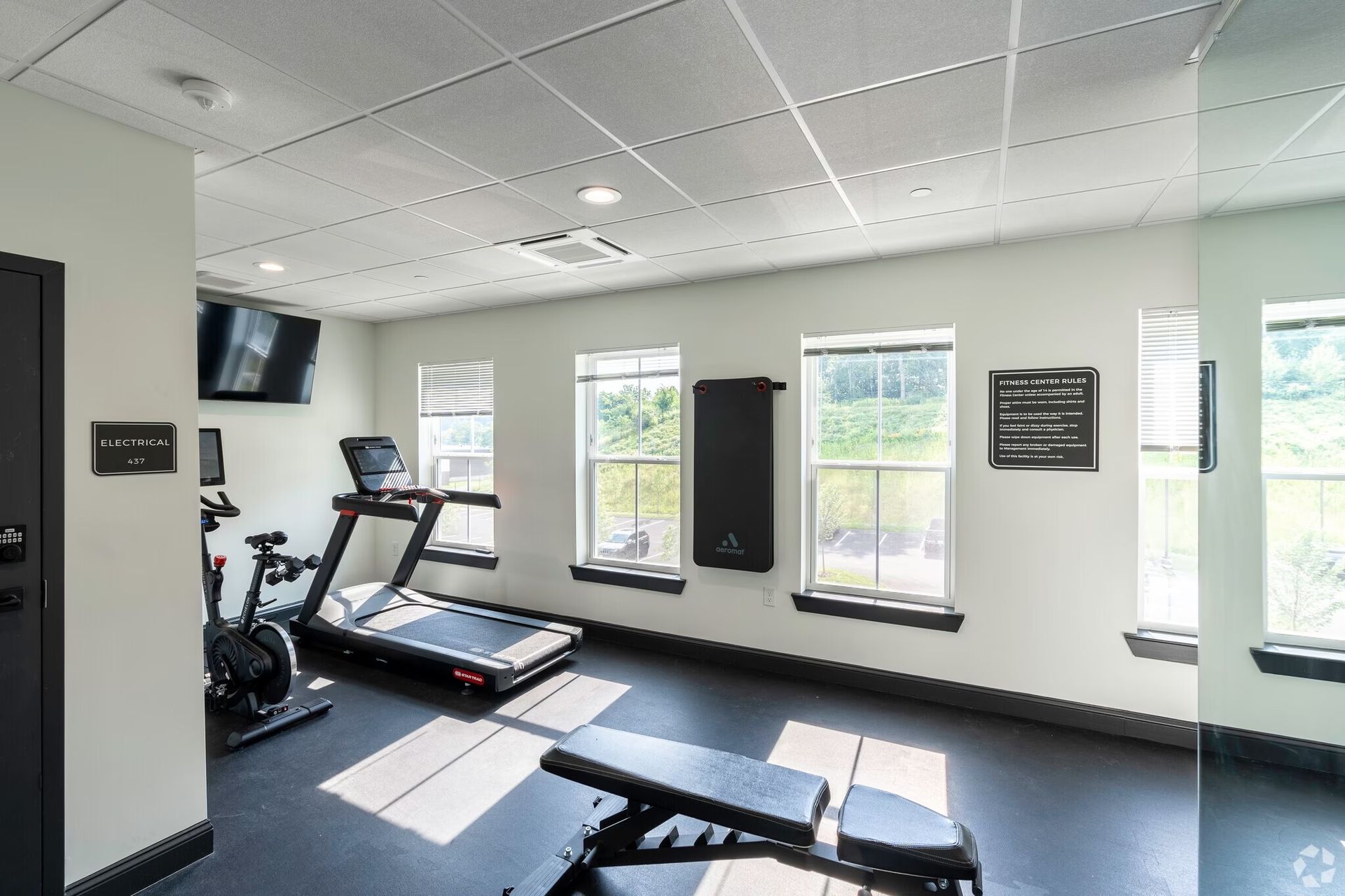 a gym with treadmills , a bike and a bench .