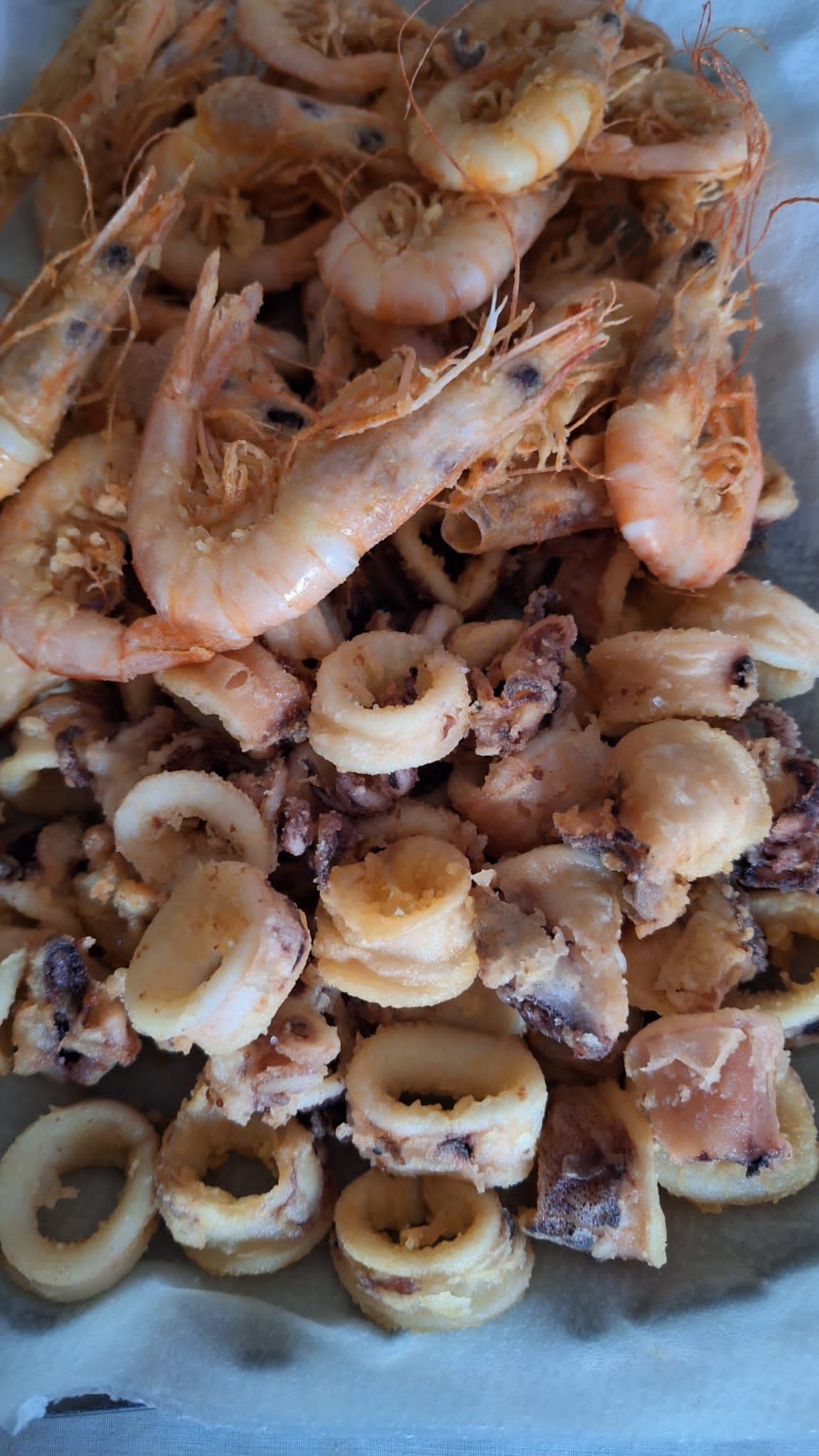 Un piatto di gamberi fritti, calamari e calamari su un tavolo.