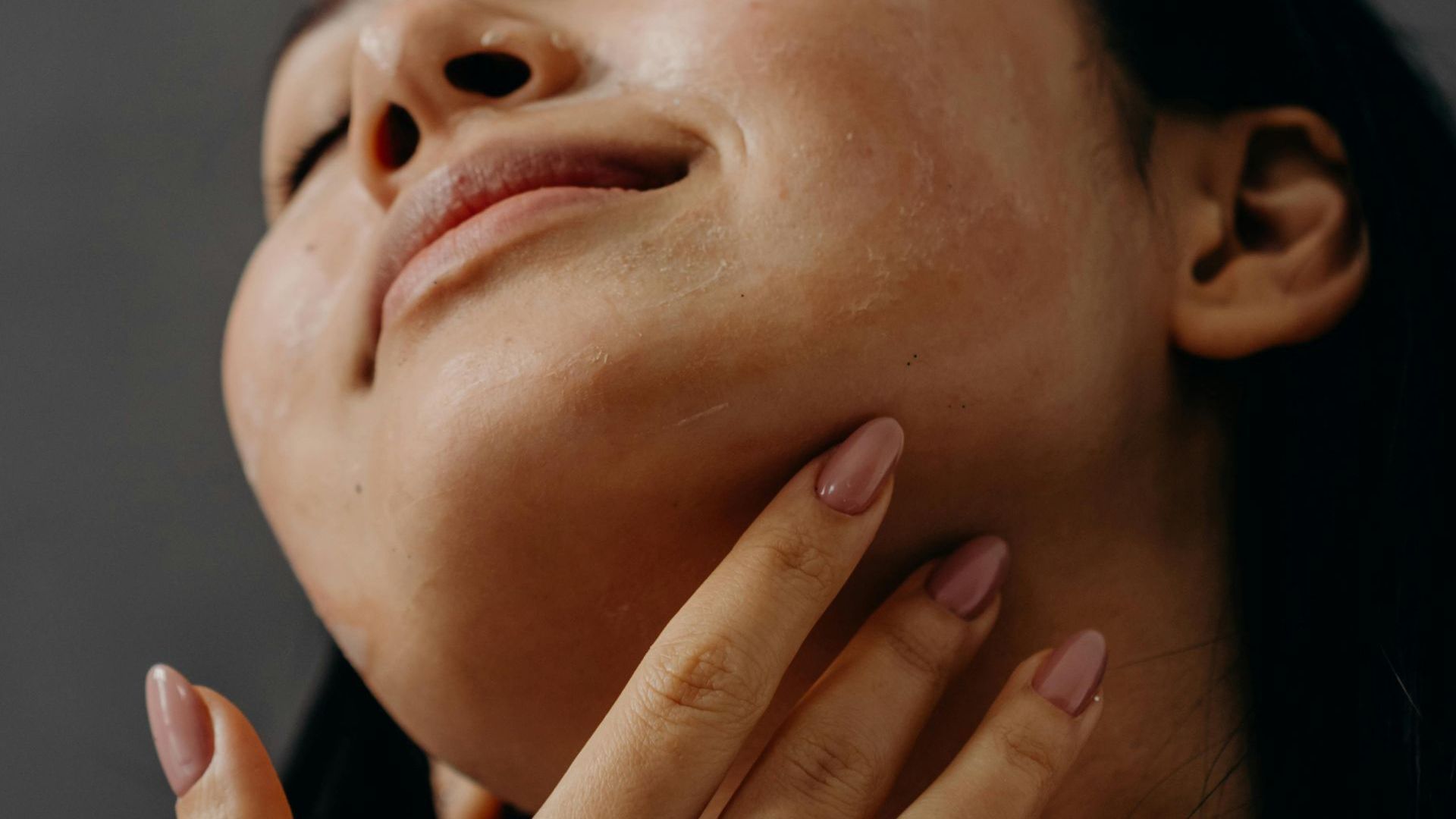 A close up of a woman 's face with her hand on her chin.