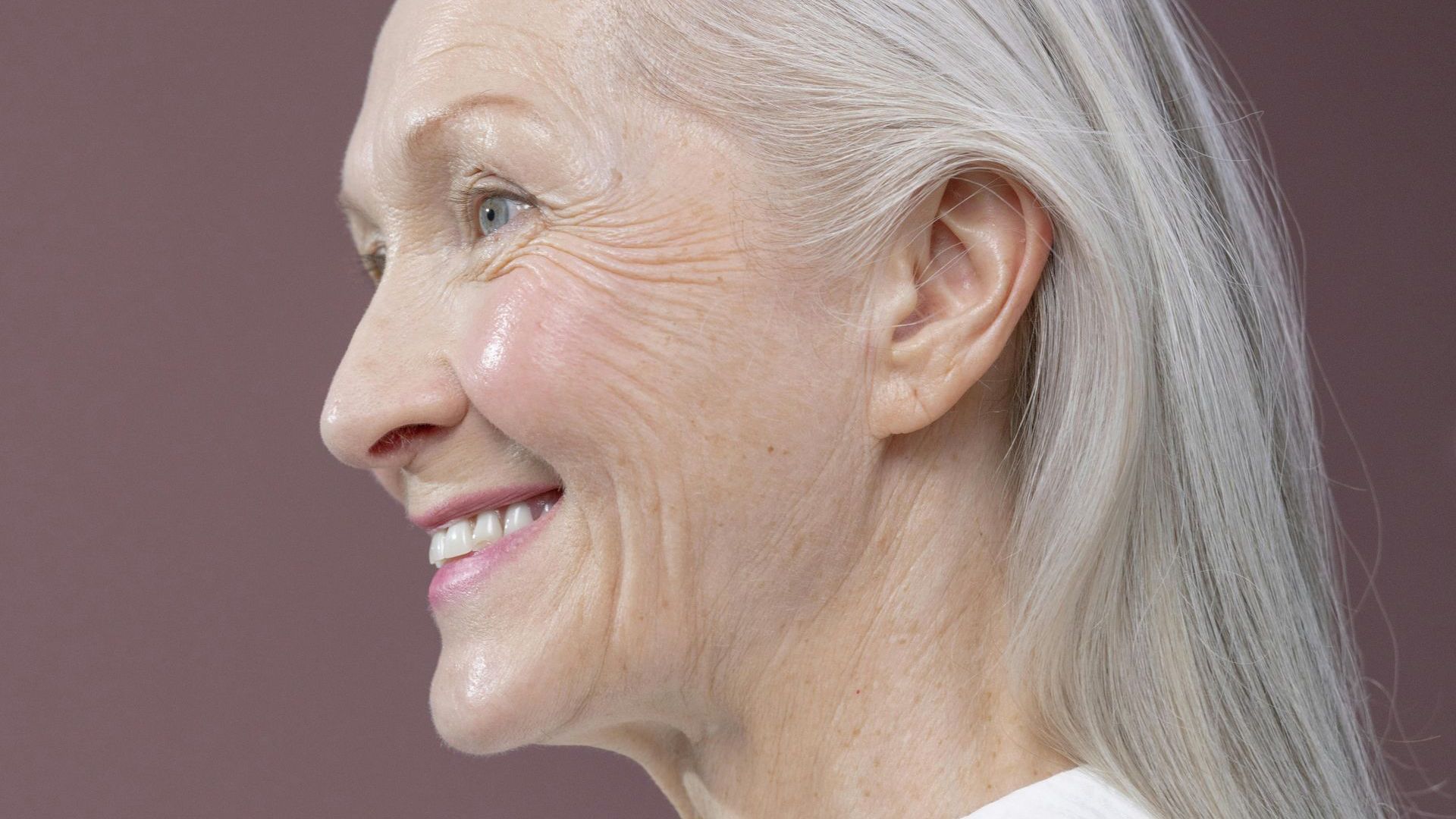 A close up of a woman 's face with gray hair smiling.