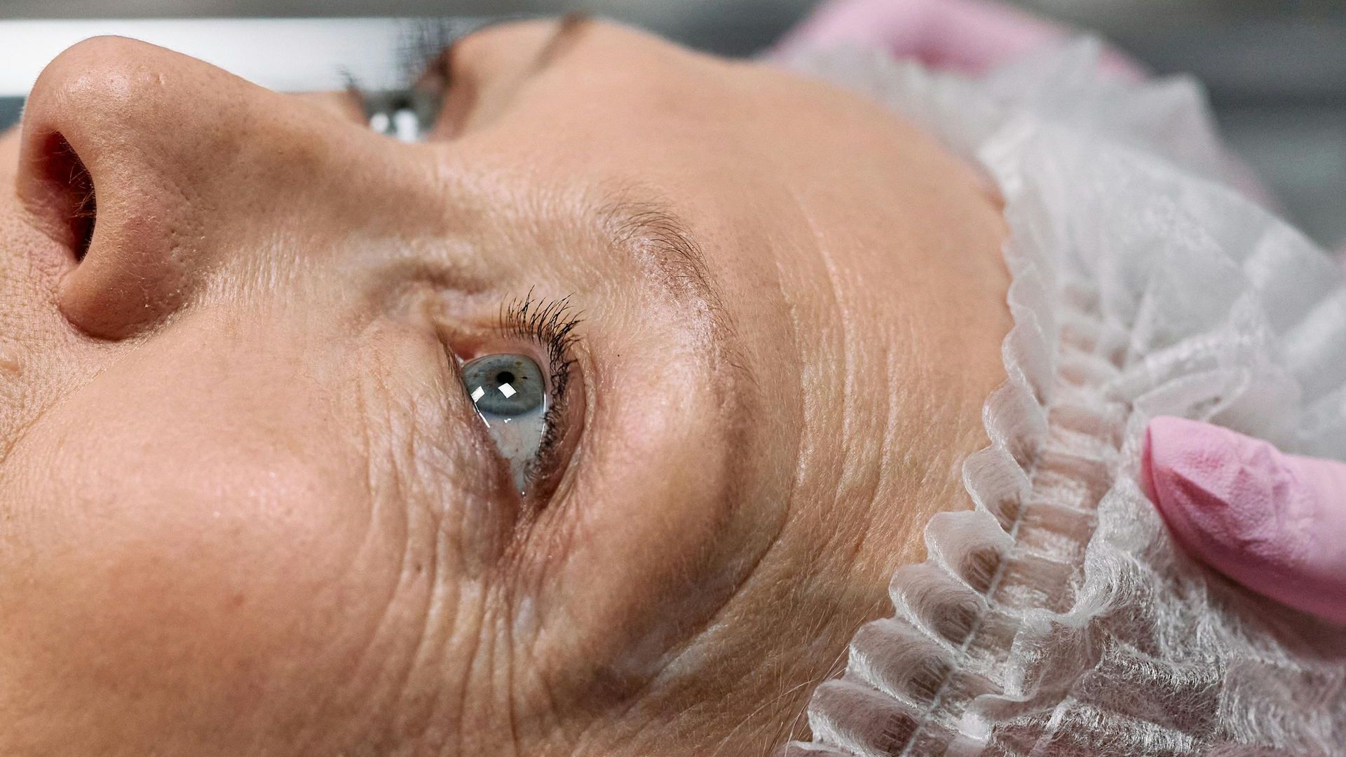 A close up of an older woman 's face with a plastic cap on her head.