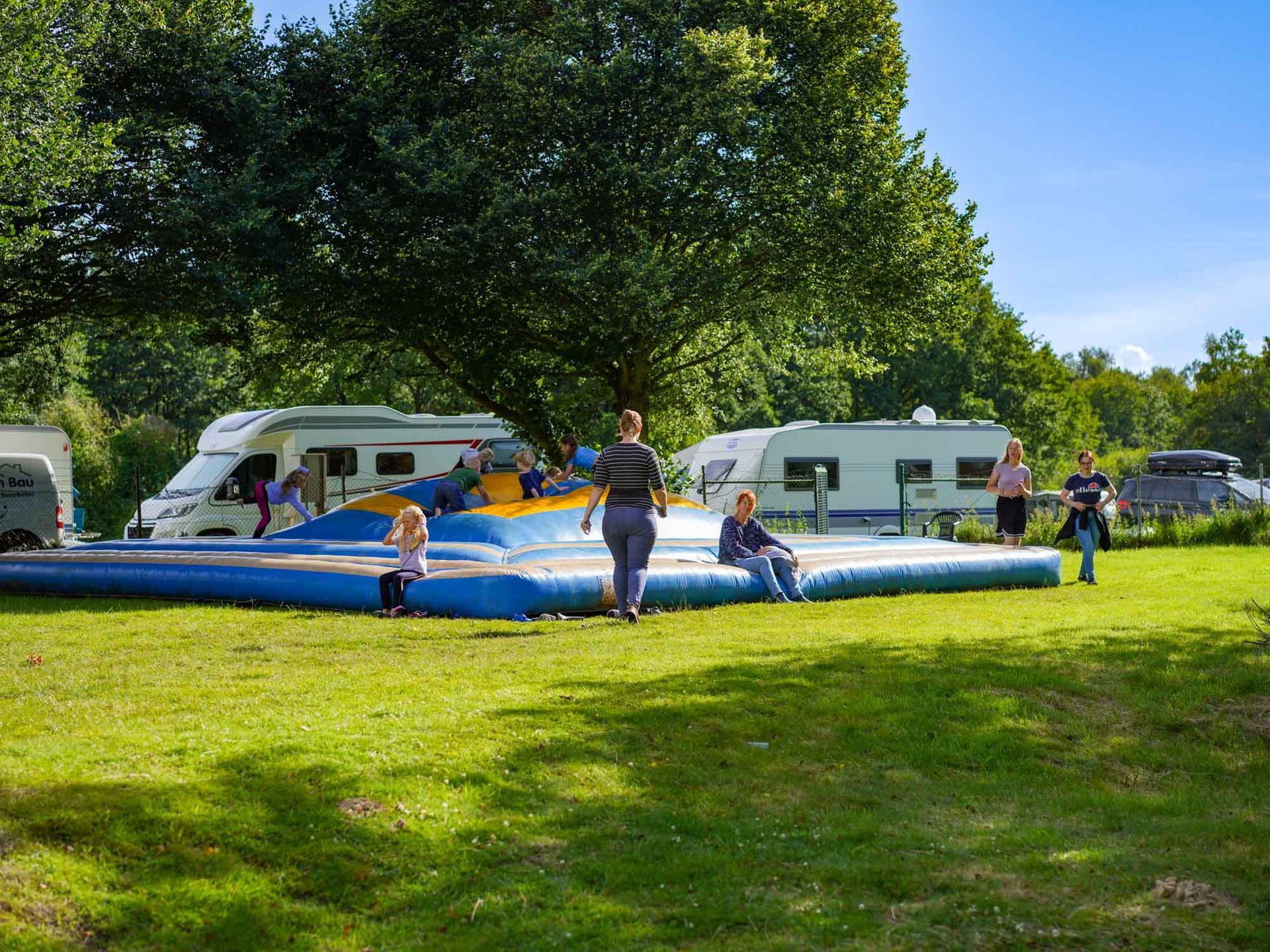 Menschen auf einer aufblasbaren Hüpfburg auf einem Campingplatz, 
