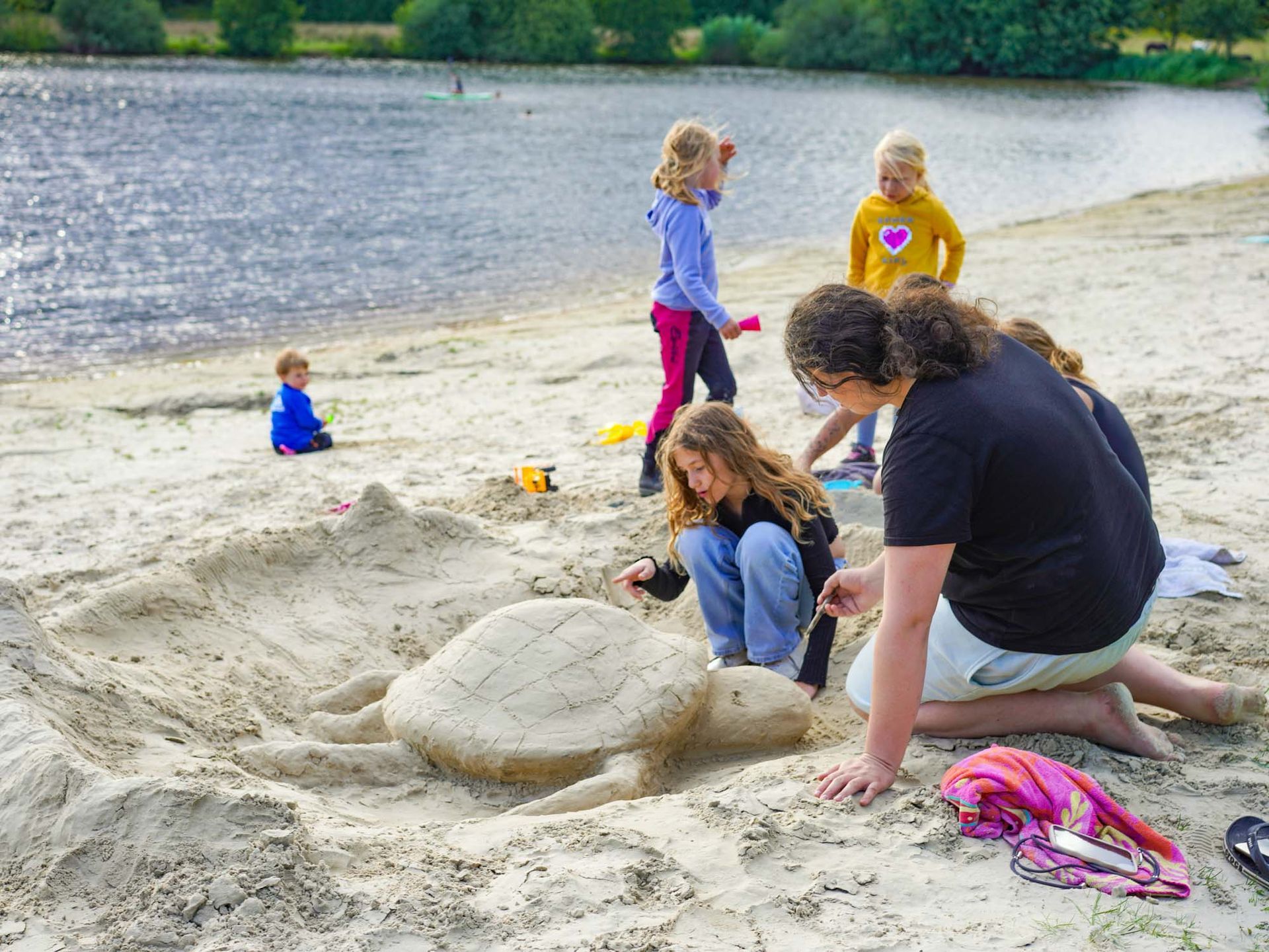 Menschen basteln an einem Strand eine Sandschildkröte