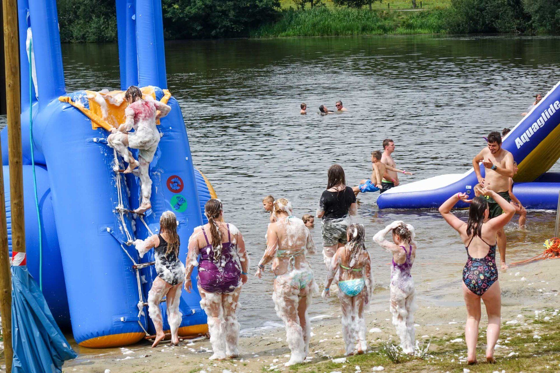 Menschen spielen an einem See mit einer aufblasbaren Rutsche.