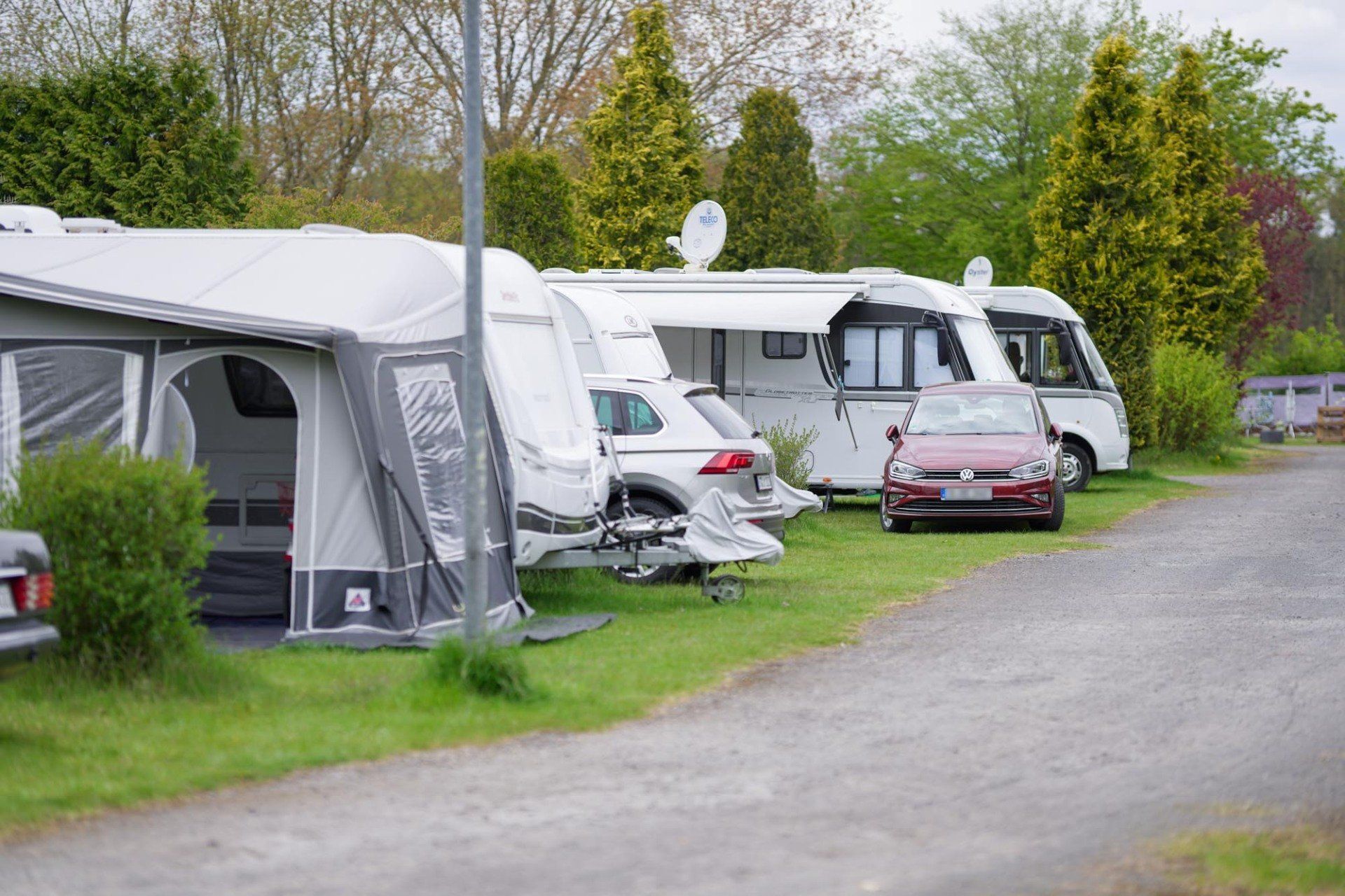 Campingfahrzeuge auf Grasboden: Wohnmobile, Wohnwagen und Autos