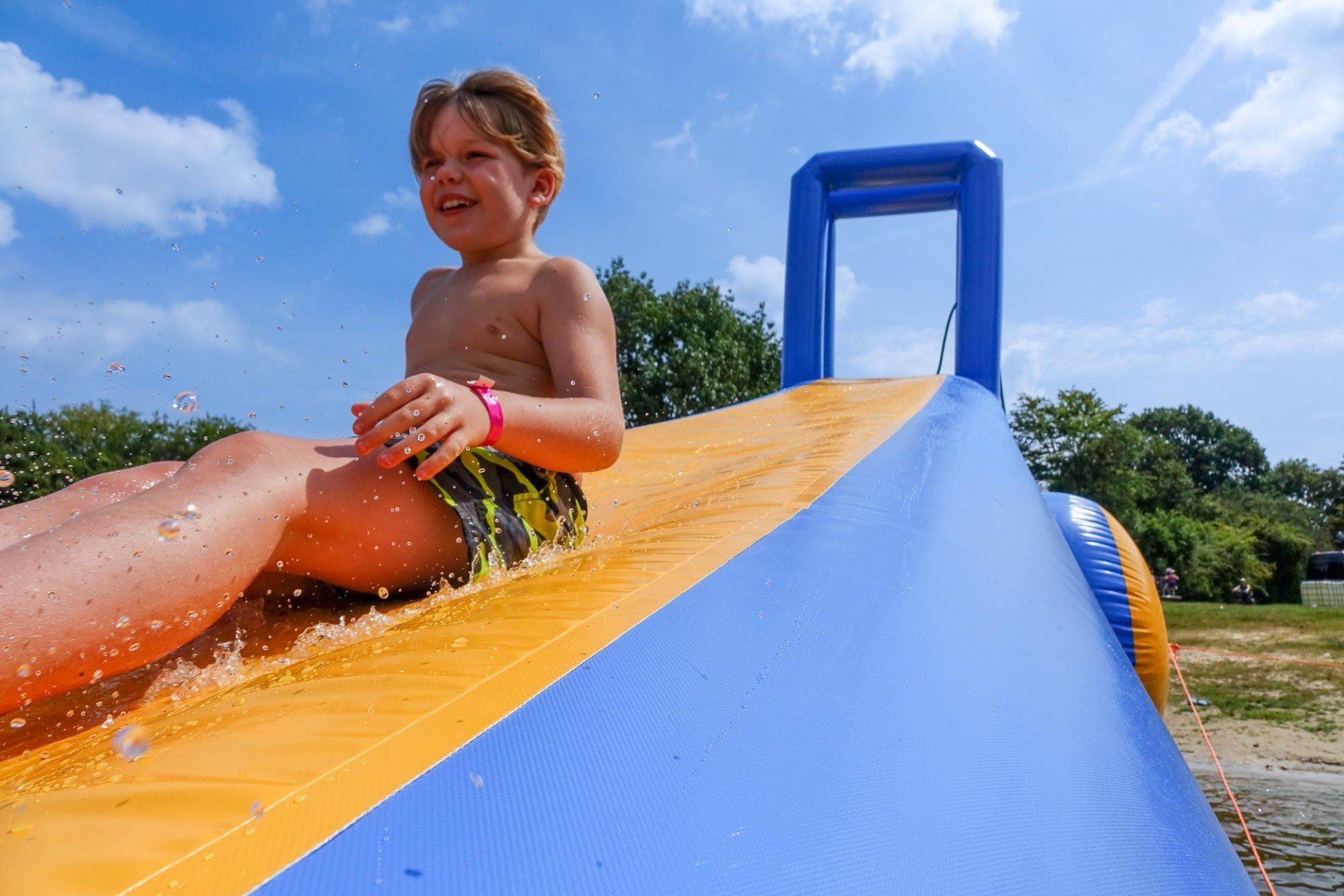 Junge rutscht eine aufblasbare Wasserrutsche hinunter