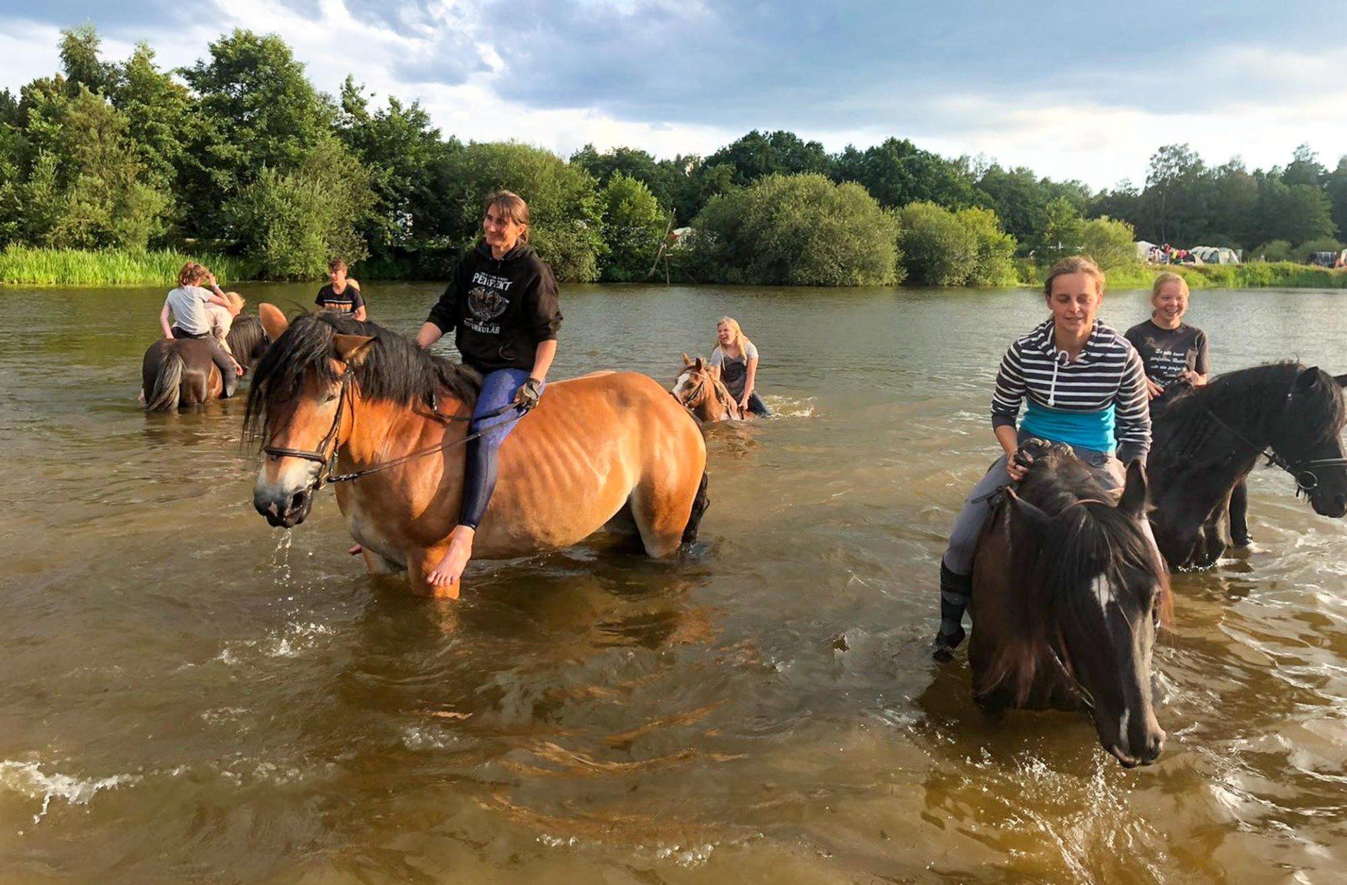 Menschen reiten auf Pferden durch Wasser