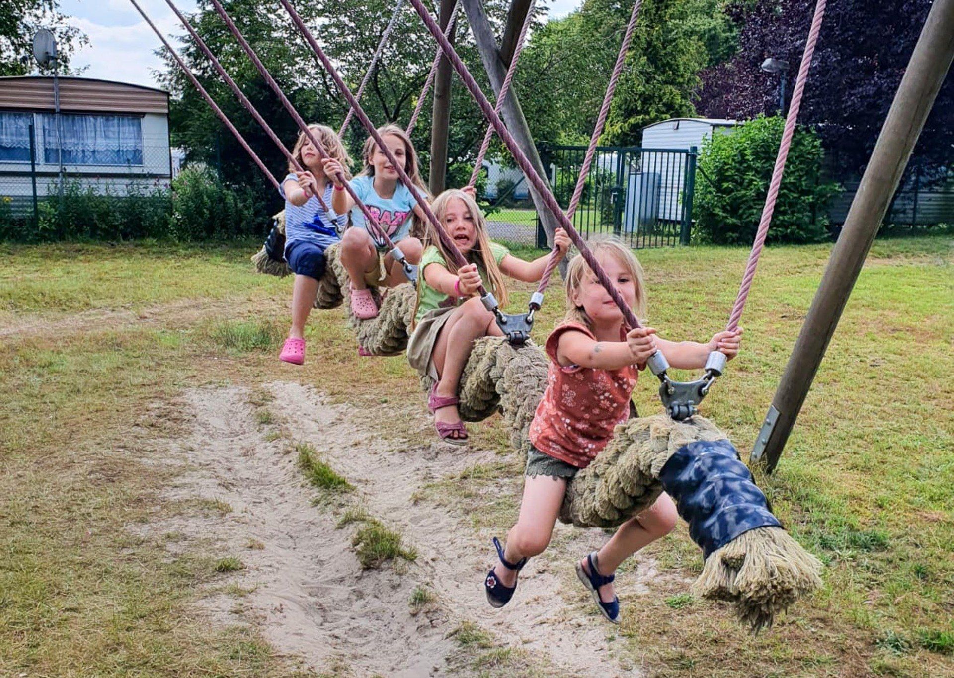 Vier junge Mädchen schaukeln auf einer Schaukel auf einem Spielplatz. 