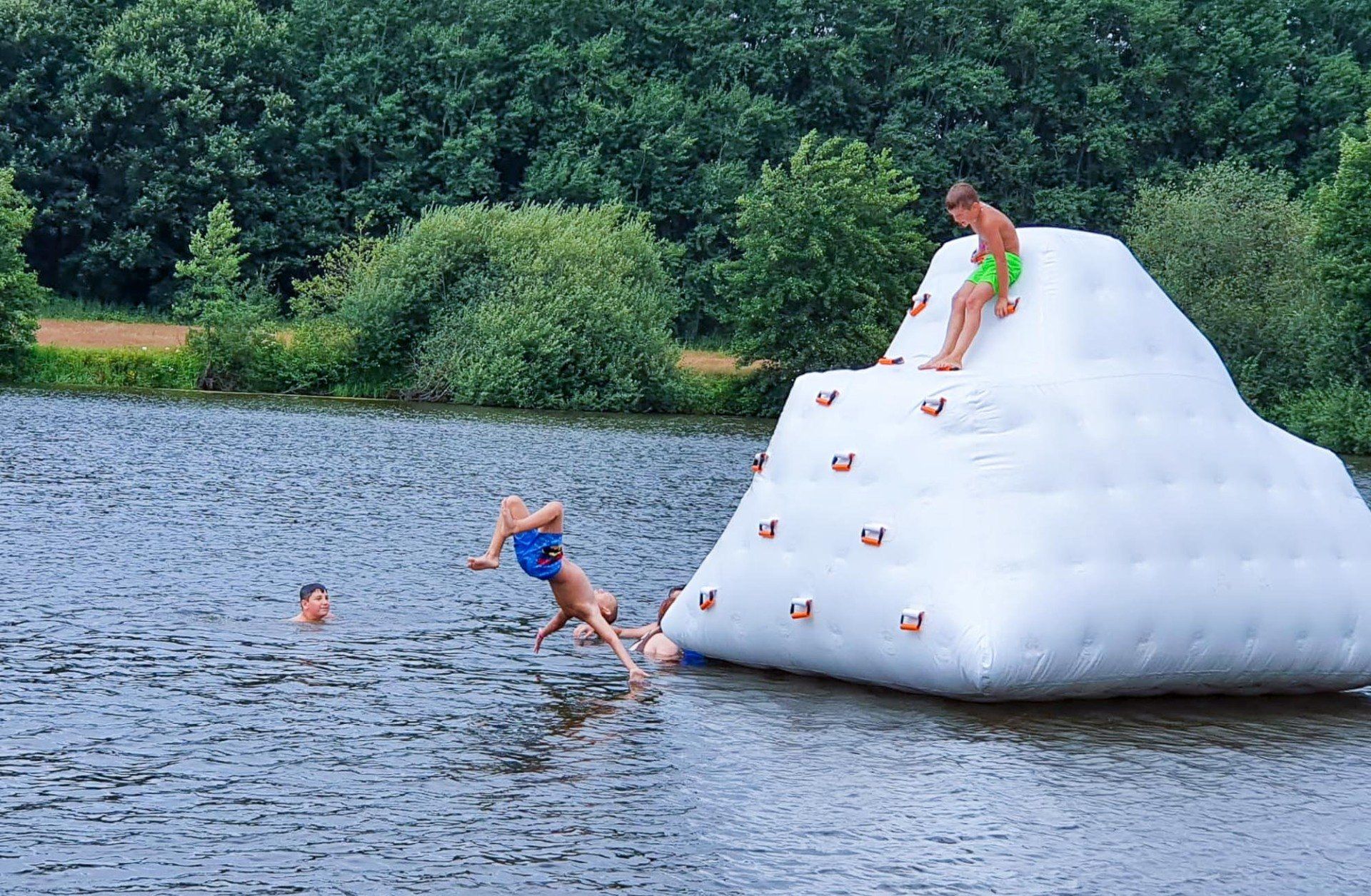 Kinder spielen auf einem aufblasbaren Kletter-Eisberg in einem See