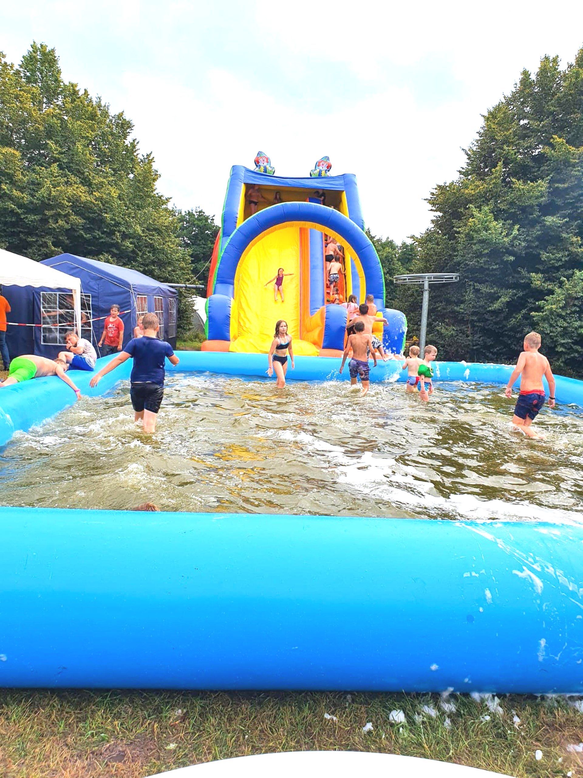 Kinder spielen in einem mit Schaumstoff gefüllten Pool mit einer großen aufblasbaren Rutsche.