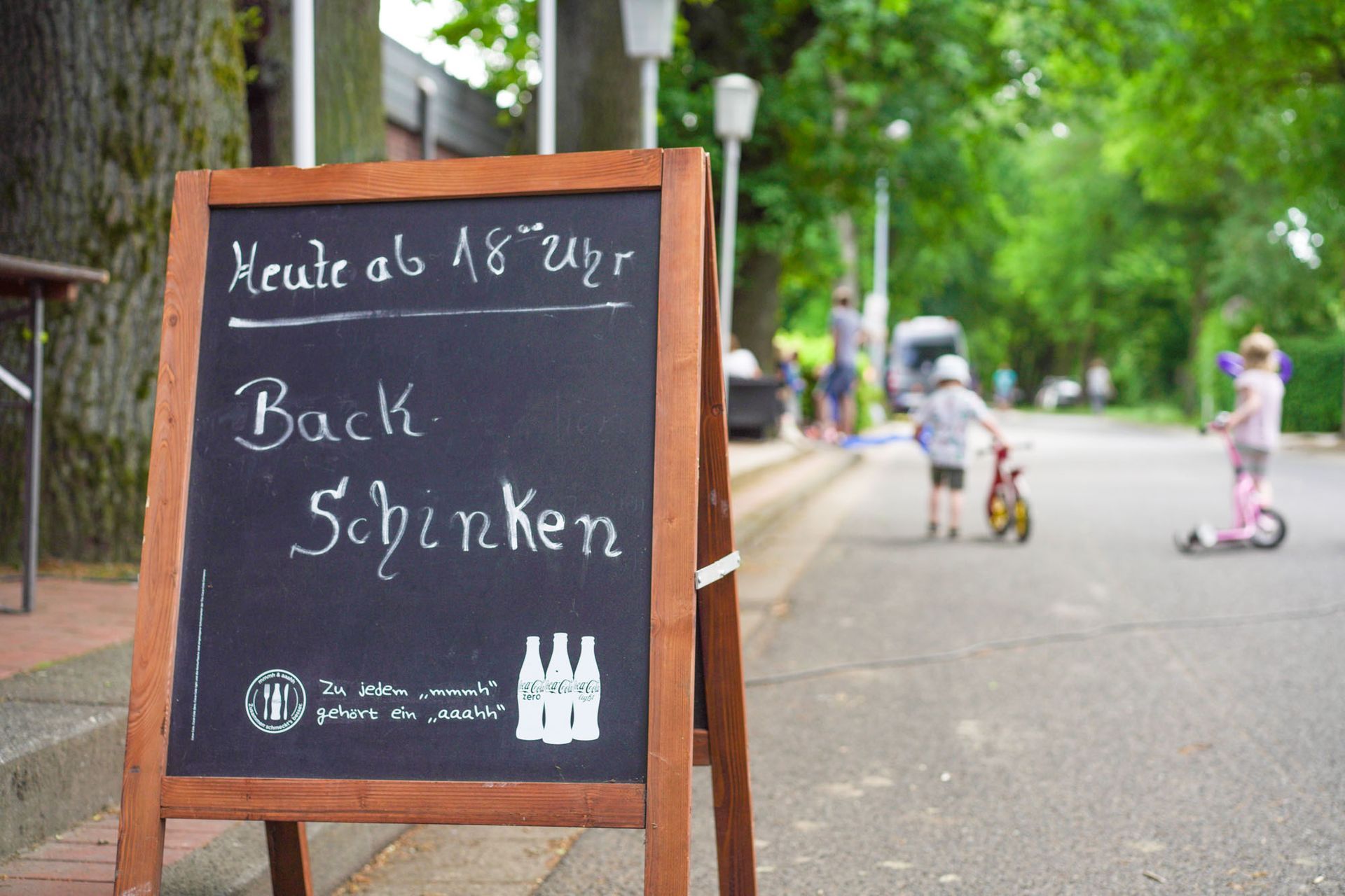 Draußen steht eine Kreidetafel mit „Backschinken“-Werbung