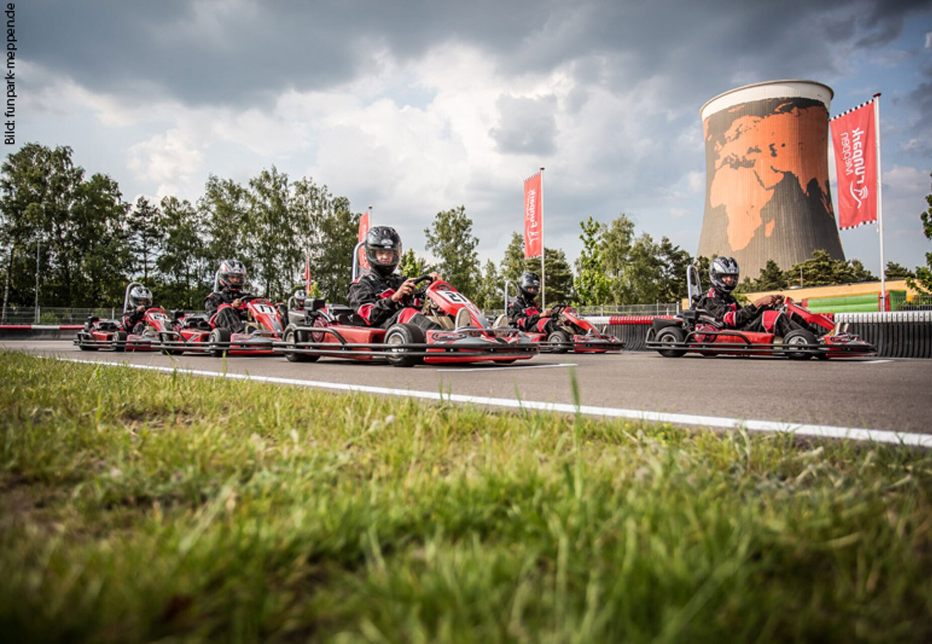 Bild von www.funpark-meppen.de Go-Karts aufgereiht auf einer Strecke; Rennfahrer tragen Helme.