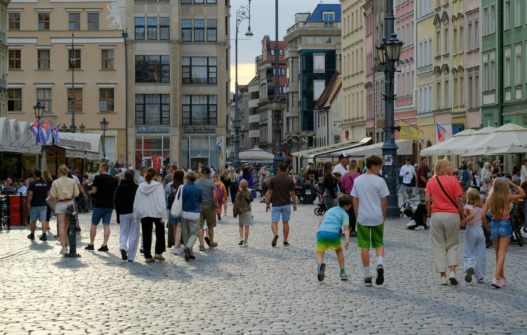 Menschen gehen auf einer Kopfsteinpflasterstraße auf einem Stadtplatz spazieren