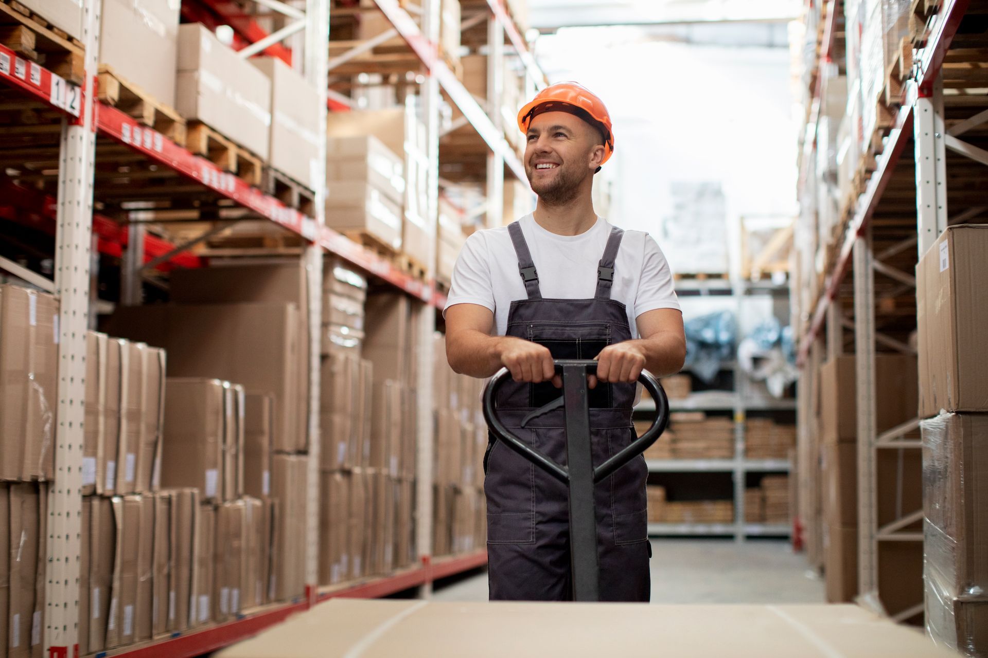 A man is pushing a pallet truck in a warehouse.