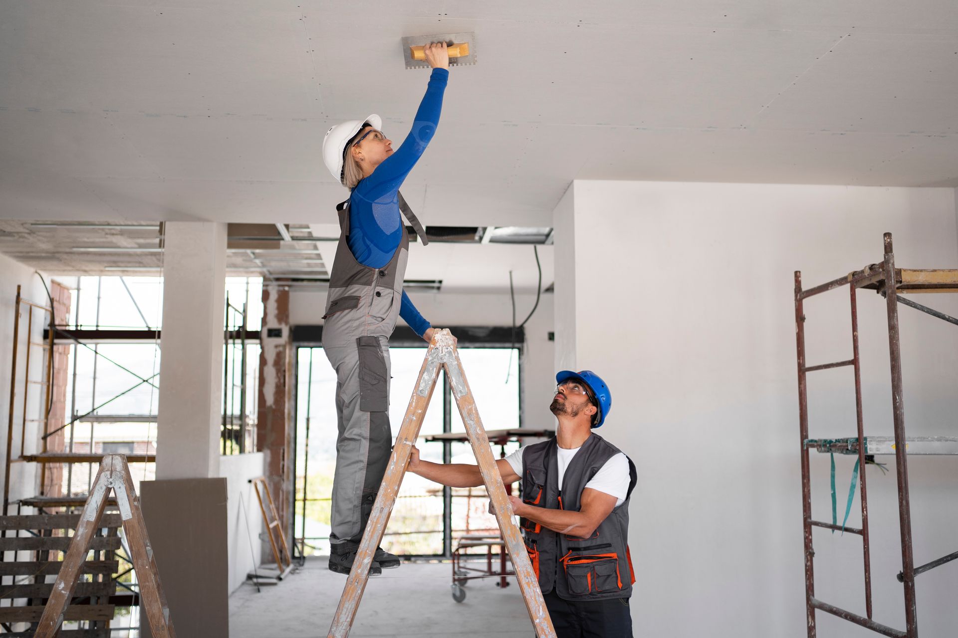 A man and a woman are working on a ceiling.