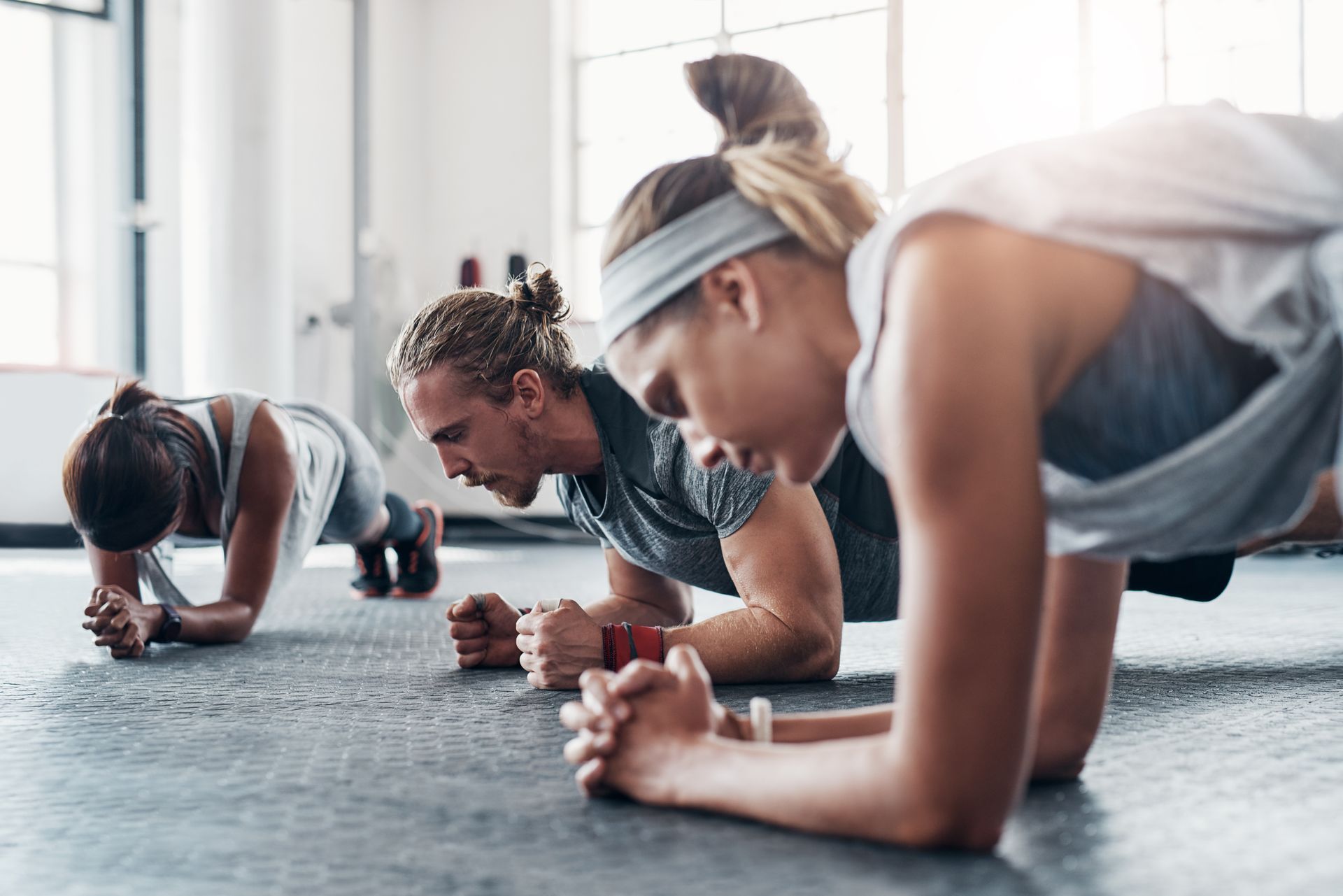 People in a gym planking on the floor.