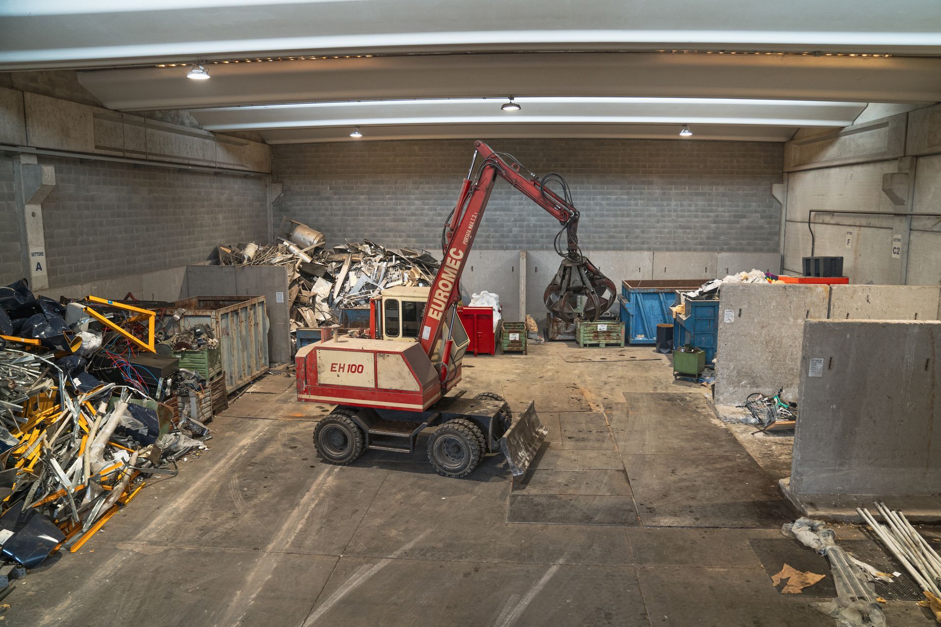 Un escavatore che seleziona rottami metallici in un centro di riciclaggio