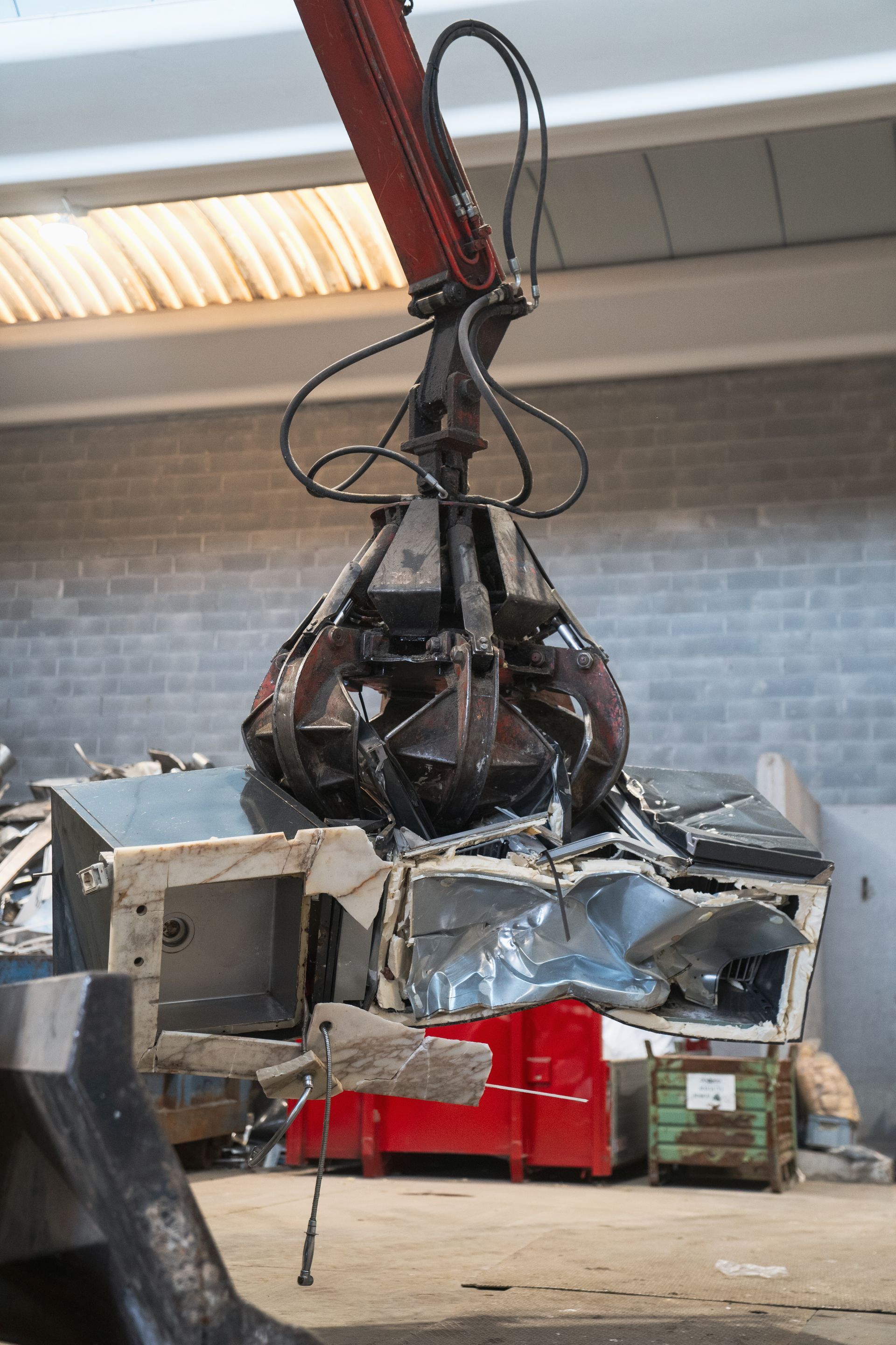 Un artiglio idraulico che schiaccia un veicolo in un impianto di riciclaggio metalli