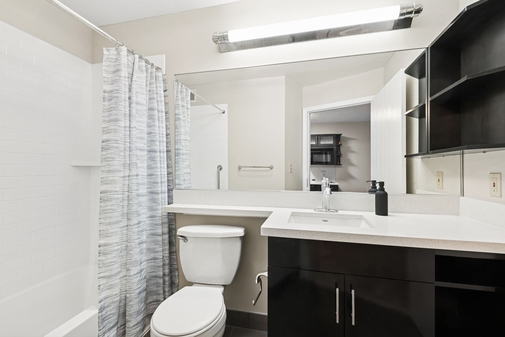 Bathroom with a toilet, sink, mirror, shower curtain, and black cabinets.