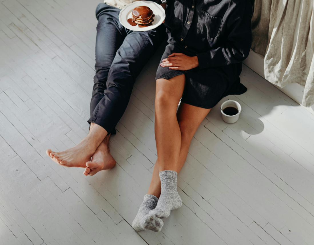 A man and a woman are sitting on the floor with a plate of food.