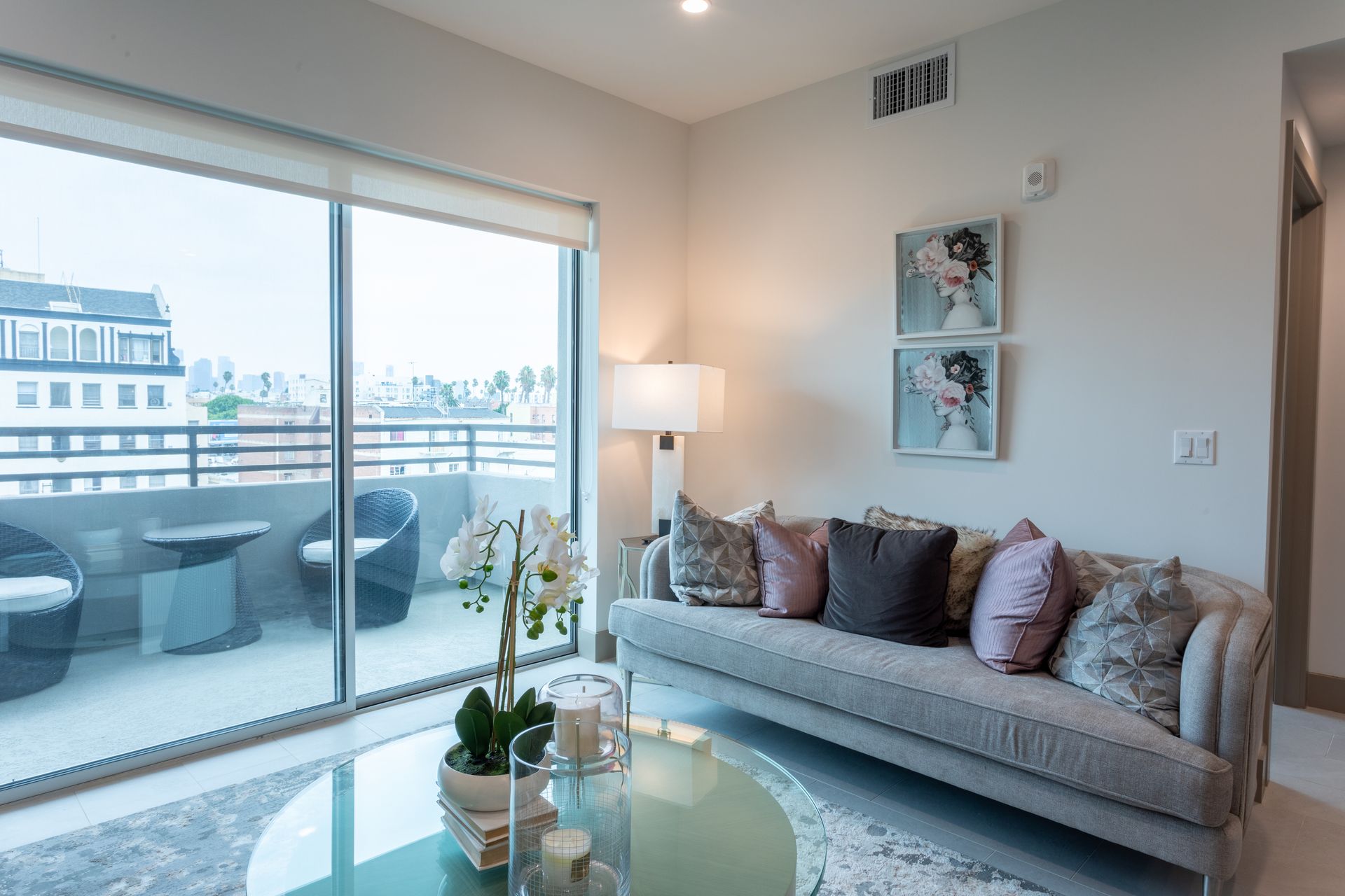 Living room with sofa, balcony, and floral arrangement.