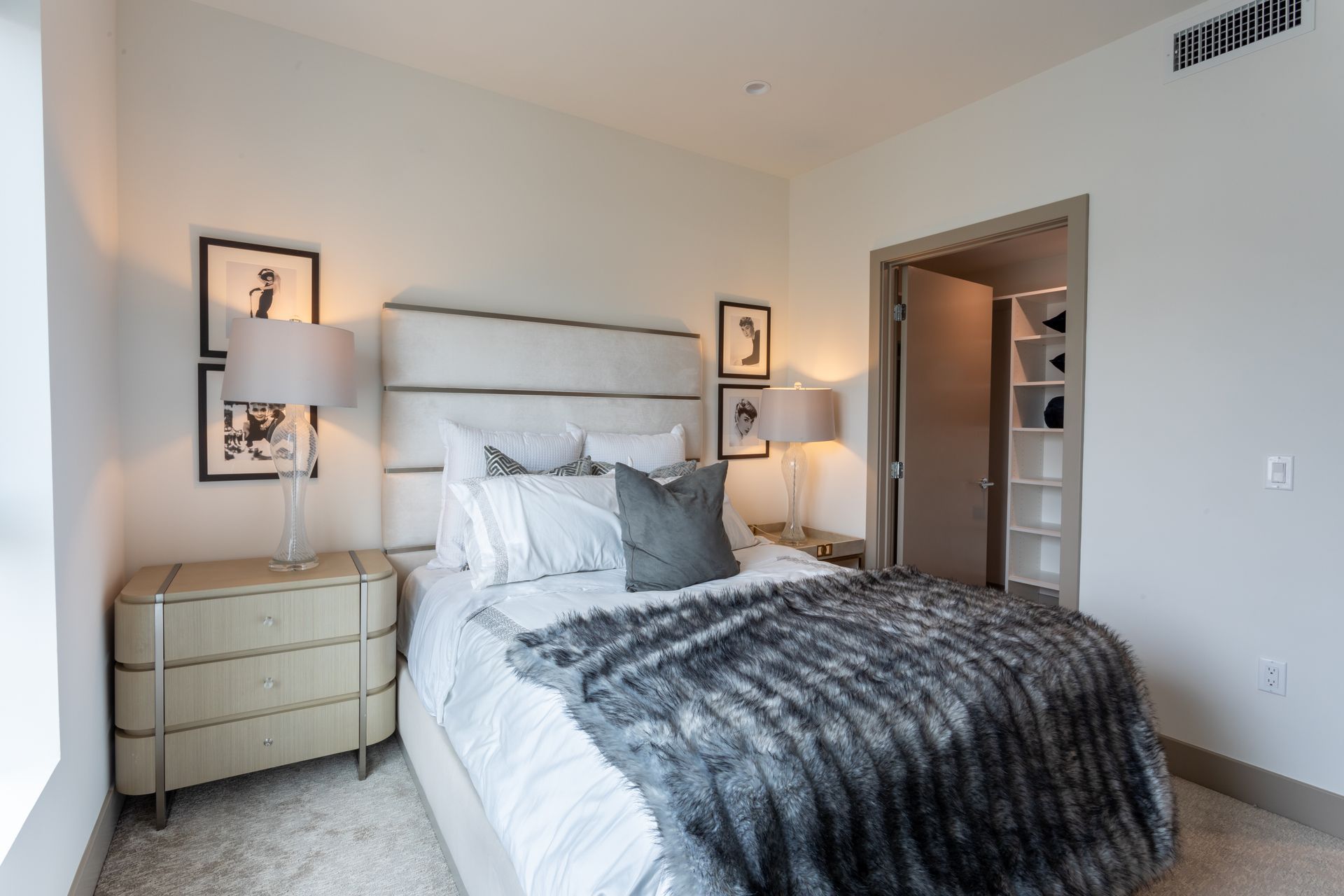 Bedroom with bed, nightstands, artwork, and open closet. Gray and neutral color scheme.