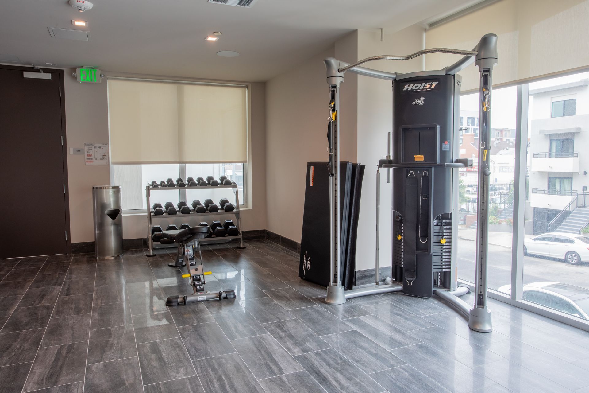 Gym with weight machines, dumbbells, a bench, and a large window.