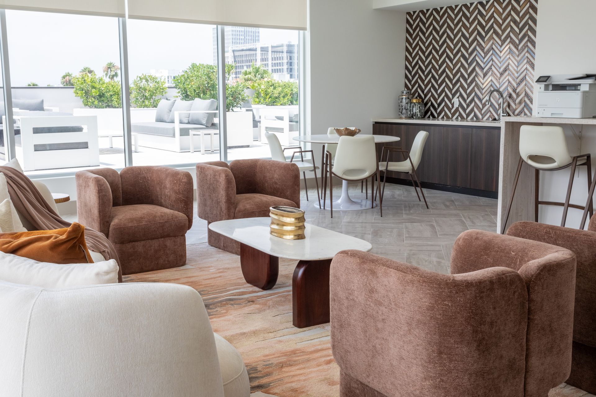 Lounge area with brown and white furniture, large windows, and a dining table.