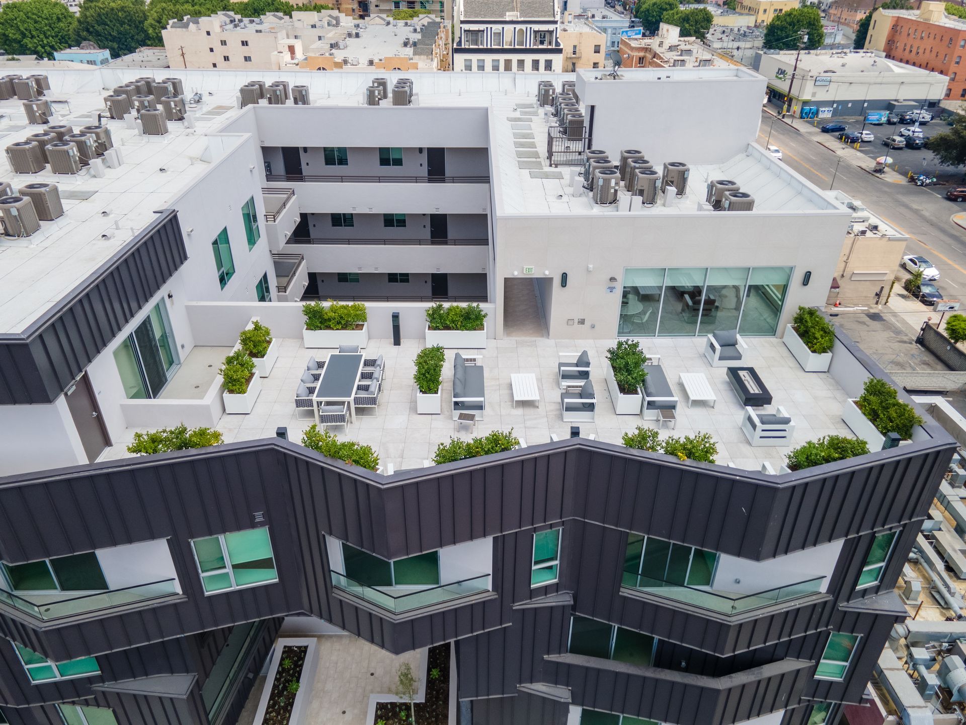 Aerial view of modern building rooftop with outdoor seating, and air conditioning units.