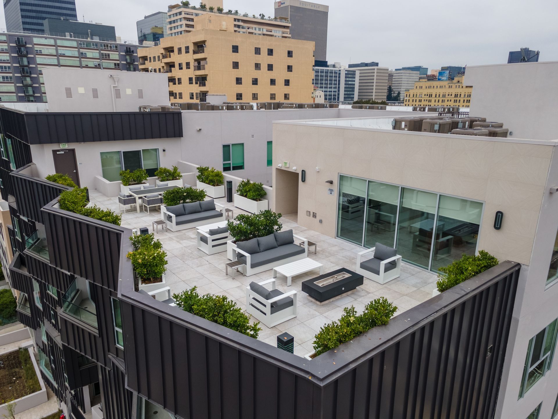 Rooftop patio with seating and plants overlooking city buildings.