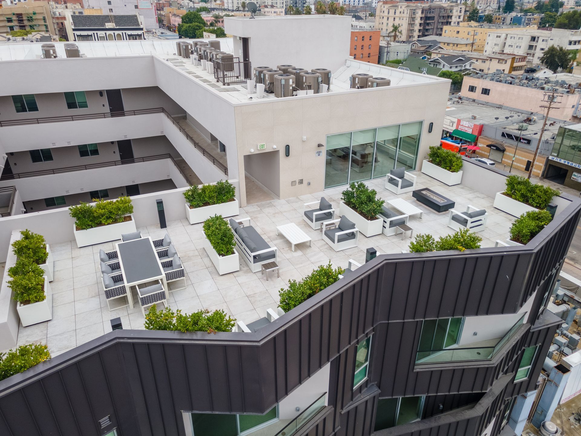 Rooftop patio with seating, planters, and cityscape view. Modern building with gray and white accents.